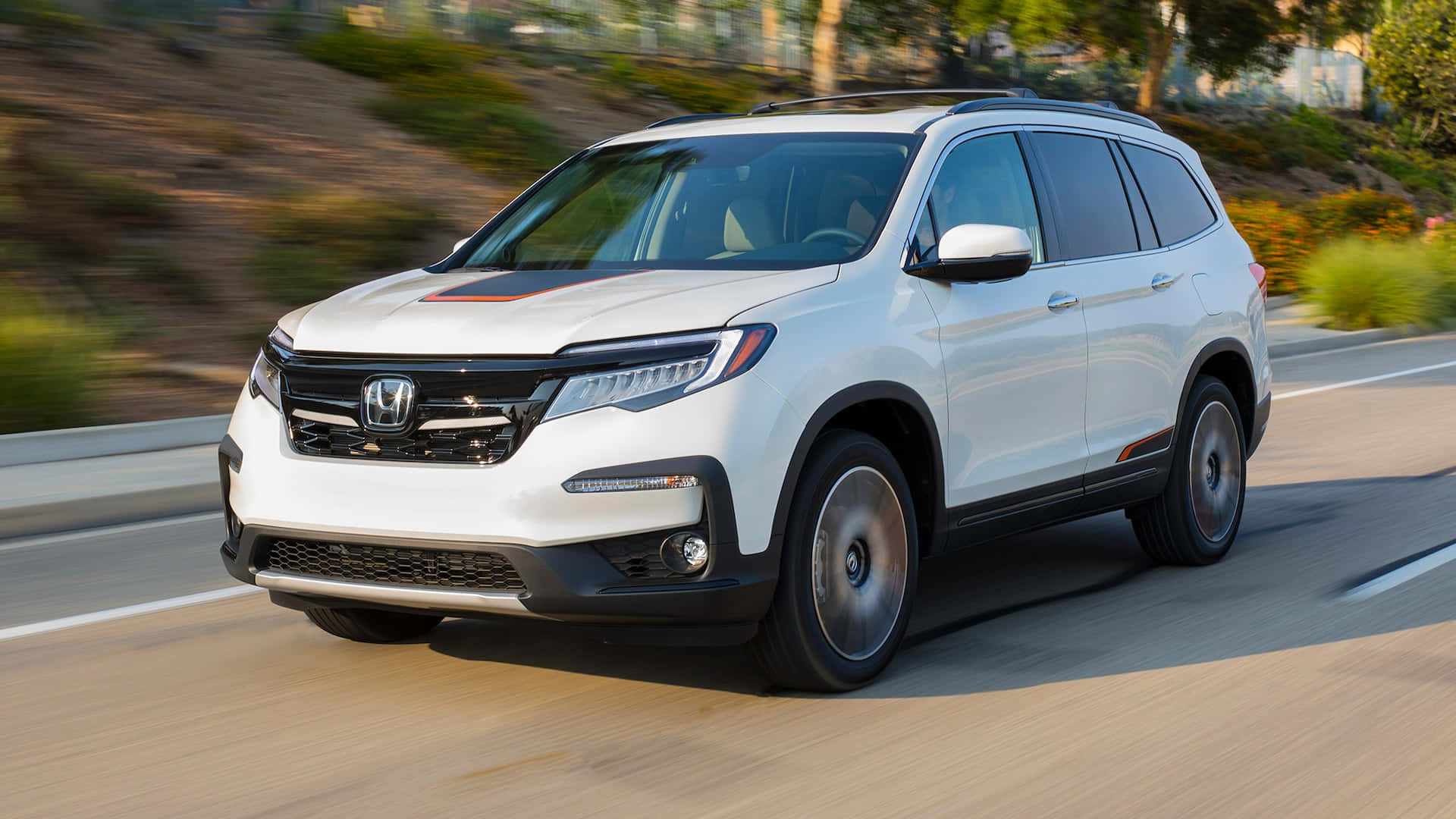 Honda Pilot 桌布 壁紙 — 一輛白色本田 Pilot SUV 在陽光明媚的高速公路上行駛，背景是模糊的綠樹和山丘。