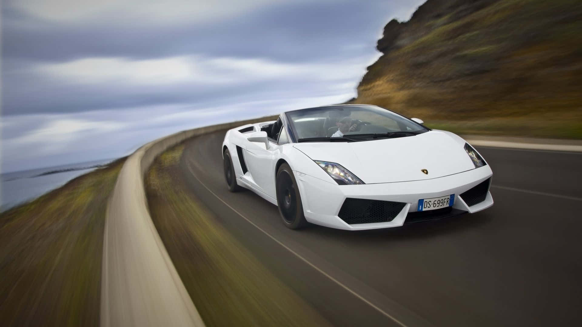 Lamborghini Gallardo 桌布 壁紙 — 一輛白色藍寶堅尼Gallardo Spyder沿著海岸公路疾馳，帶有動態模糊和陰天。