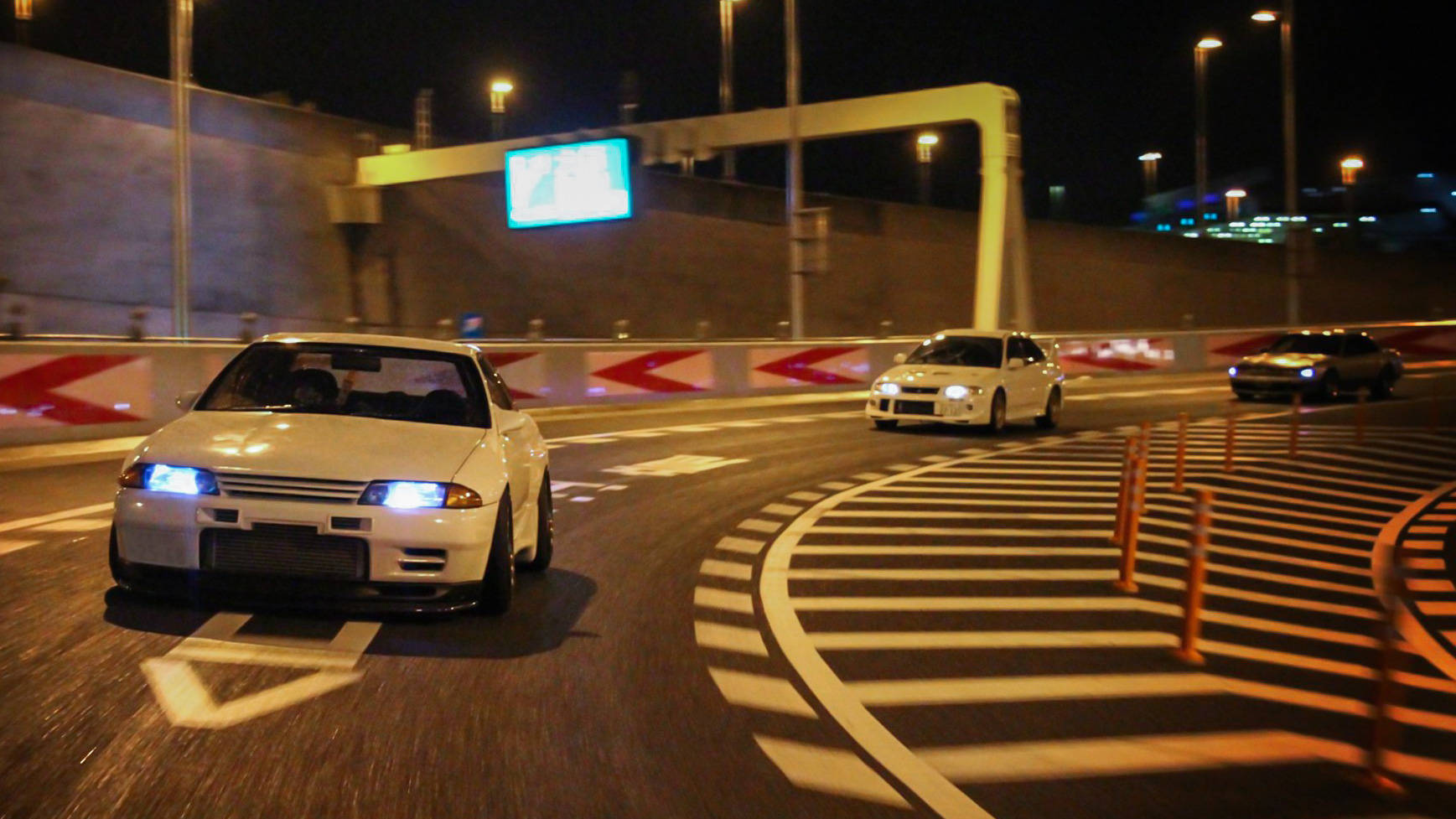 白色賽車在夜間賽道上疾馳，車頭燈發光。 — JDM汽車 壁紙