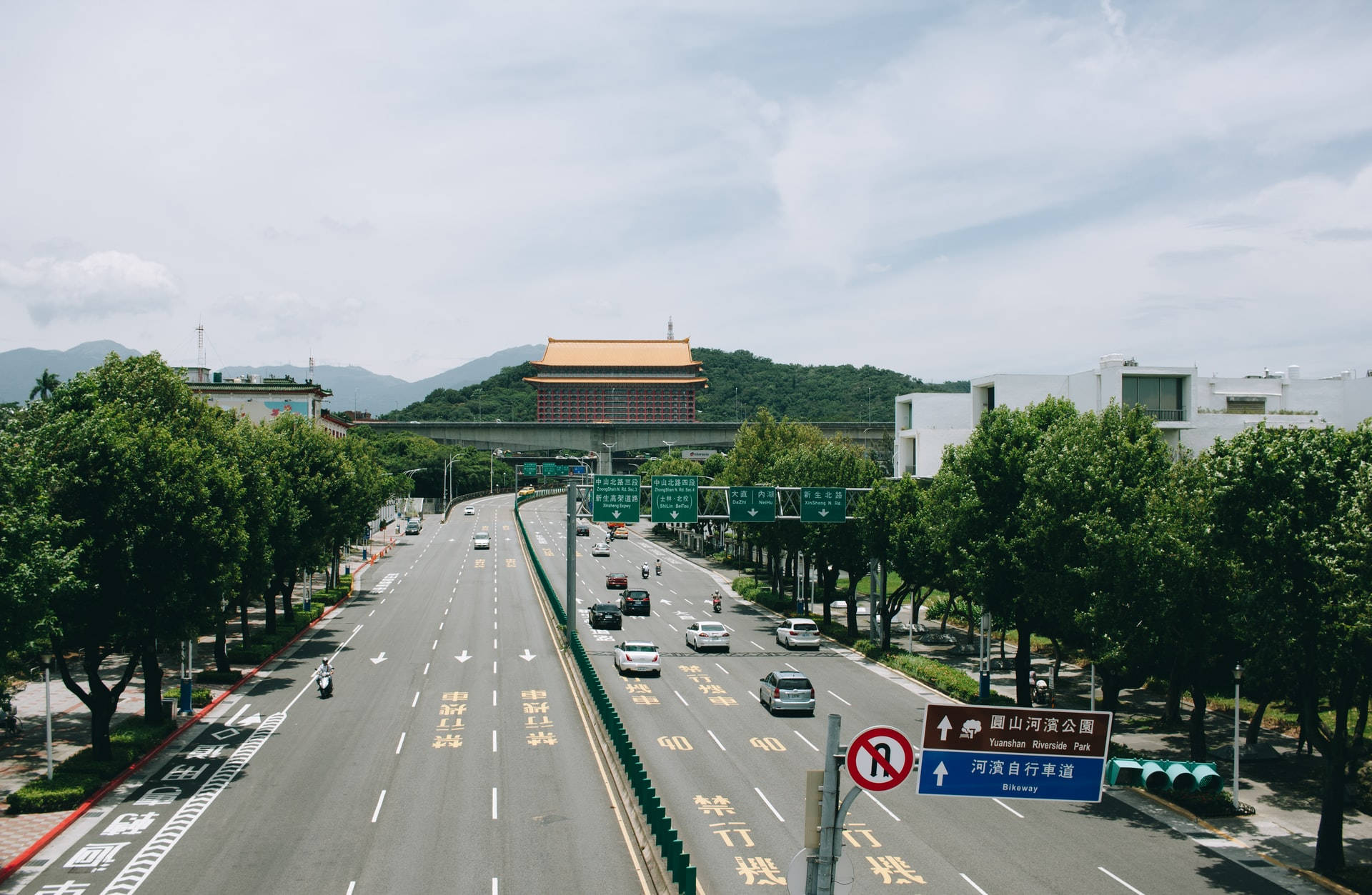 寬闊的高速公路，有汽車和樹木，通向山上的傳統建築。 — 台北 壁紙