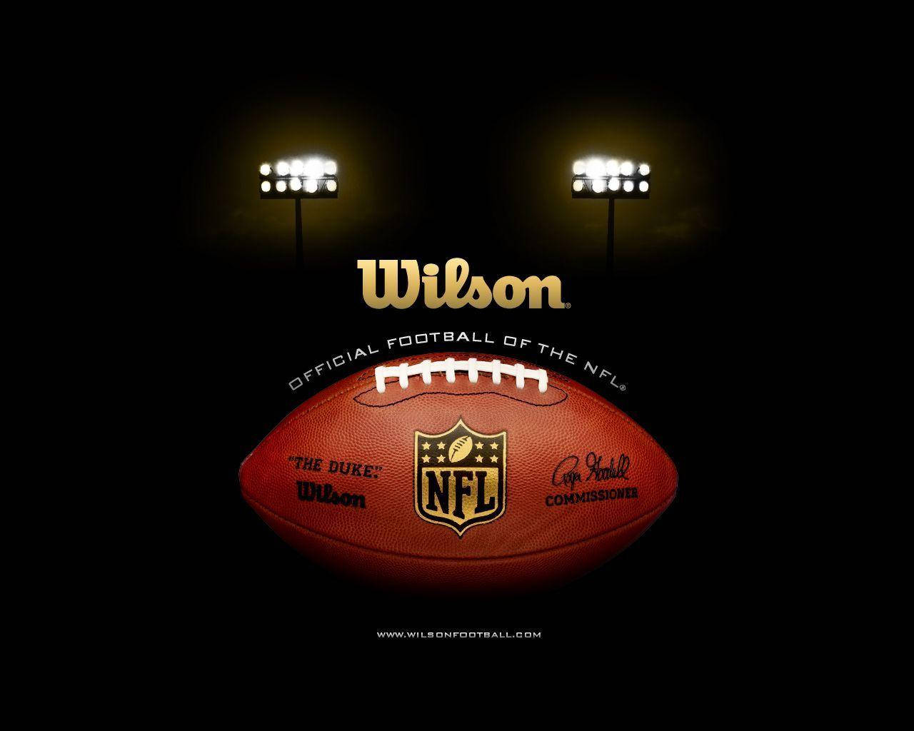NFL 美式足球 桌布 壁紙 — Wilson NFL 美式足球在球場燈光下發光，黑色背景，帶有官方品牌標誌。
