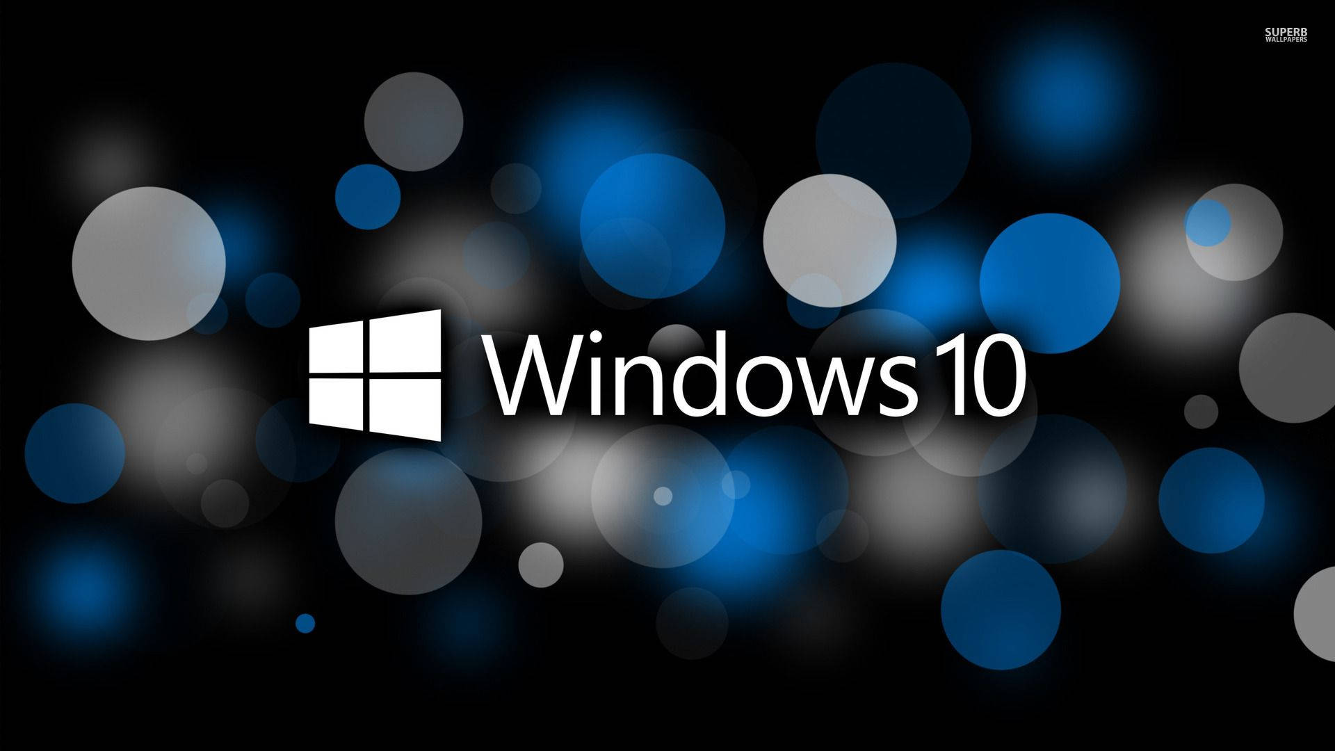 Windows 10 高畫質 桌布 壁紙 — Windows 10 標誌以白色文字和圖示居中顯示在深色背景上，帶有發光的藍色和灰色散景圓圈。