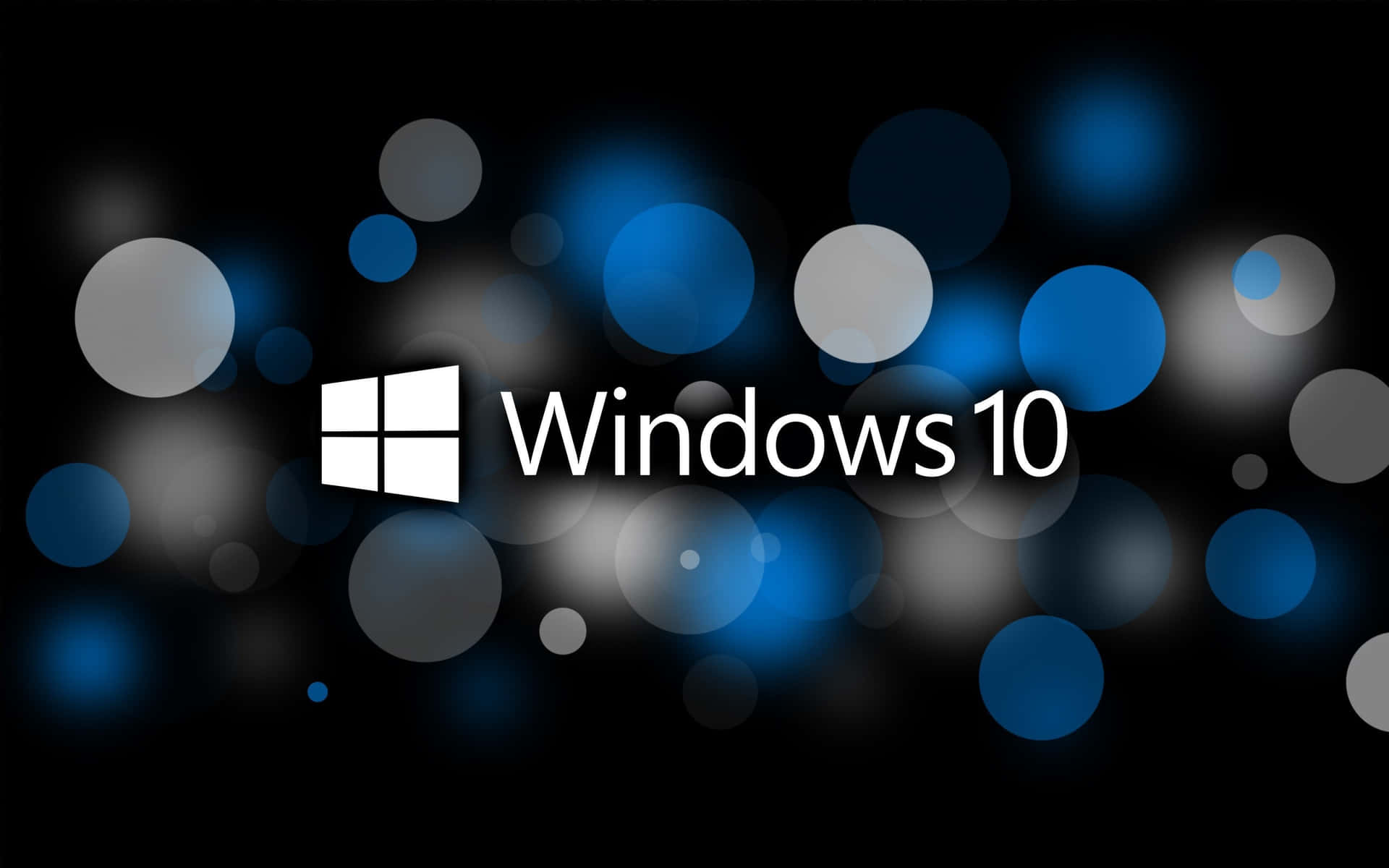 Windows 10 桌布 壁紙 — Windows 10 標誌以白色文字和視窗圖示居中顯示在深色背景上，帶有發光的藍色和灰色散景圓圈。