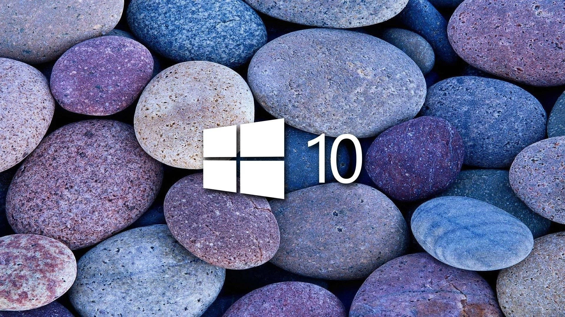 Windows 10 高畫質 桌布 壁紙 — Windows 10 標誌居中放置在平滑的多色河石床上，顏色有藍色、紫色和灰色。