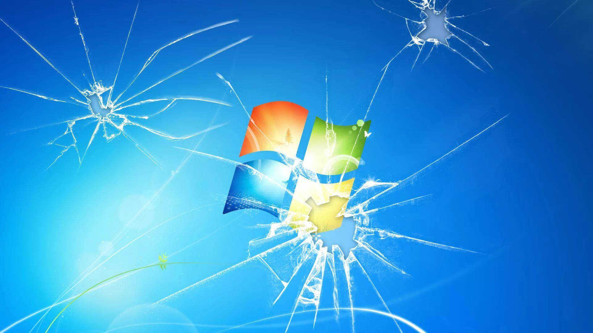 broken monitor 桌布 壁紙 — Windows 標誌穿過破裂的玻璃碎裂在明亮的藍色漸變背景上。