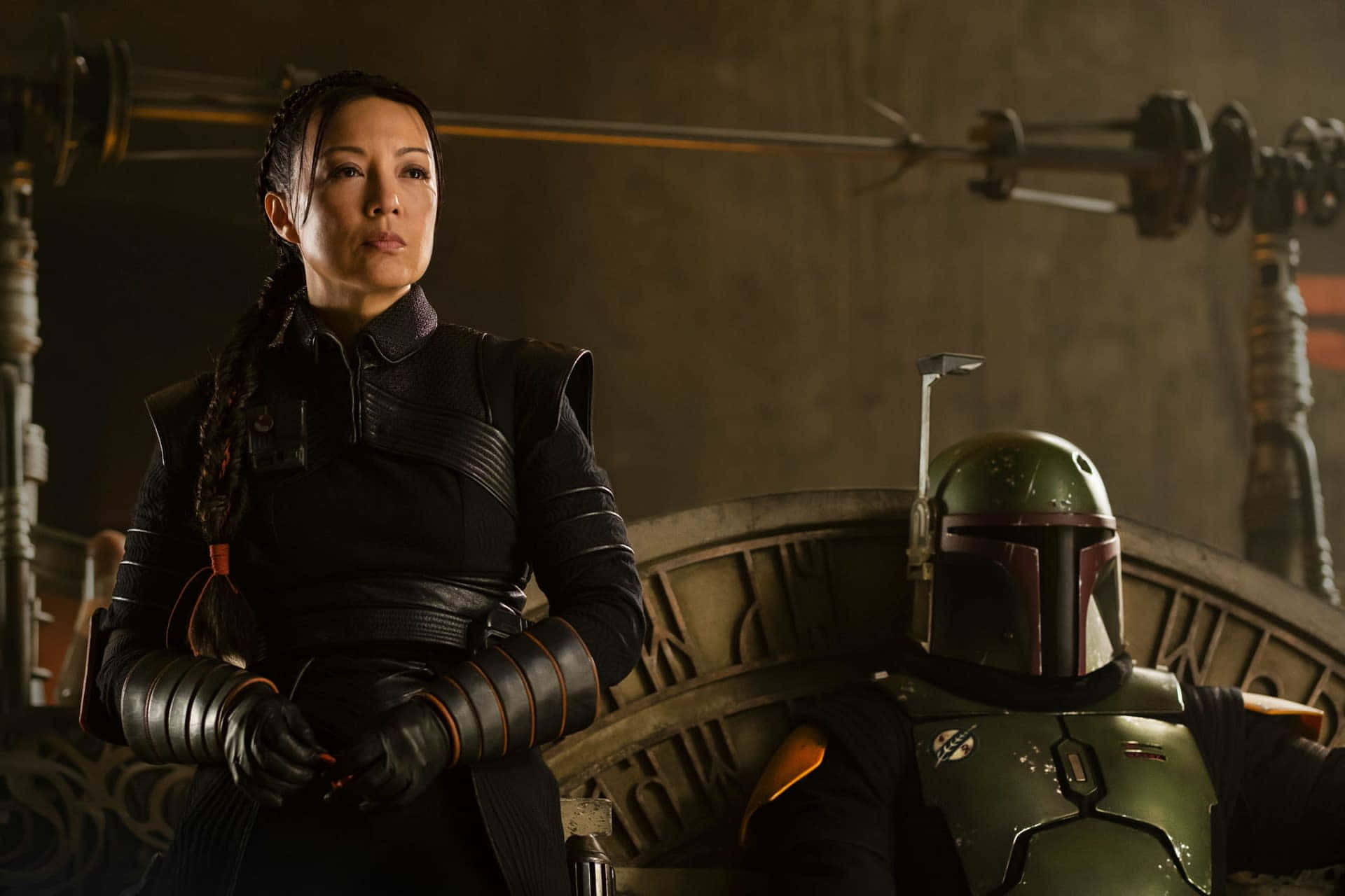 Ming Na Wen 桌布 壁紙 — 一名身穿黑色盔甲的女子站在一個戴著綠色頭盔的賞金獵人身旁，身處昏暗的工業環境中。