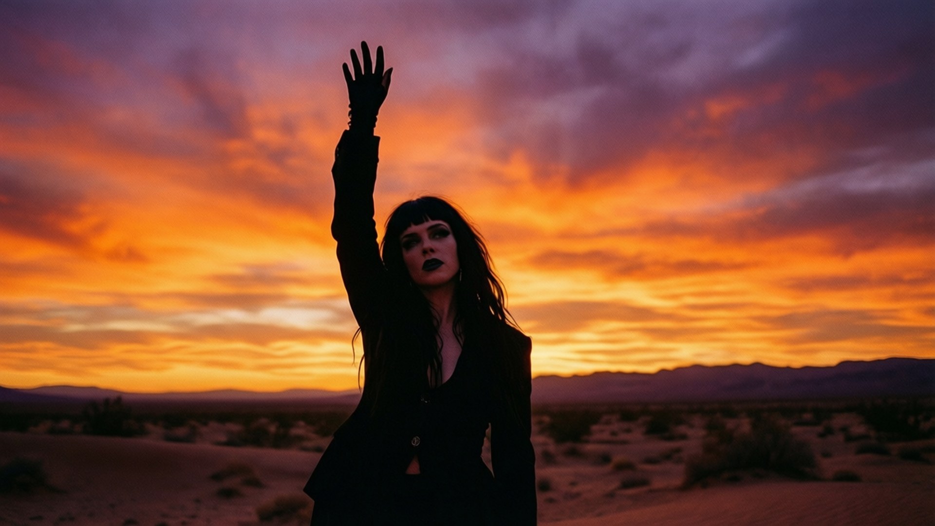 Desert Sunset Silhouette 壁紙 — 一個黑色剪影的女人舉起她戴手套的手，對著熾熱的橙色和紫色沙漠日落。
