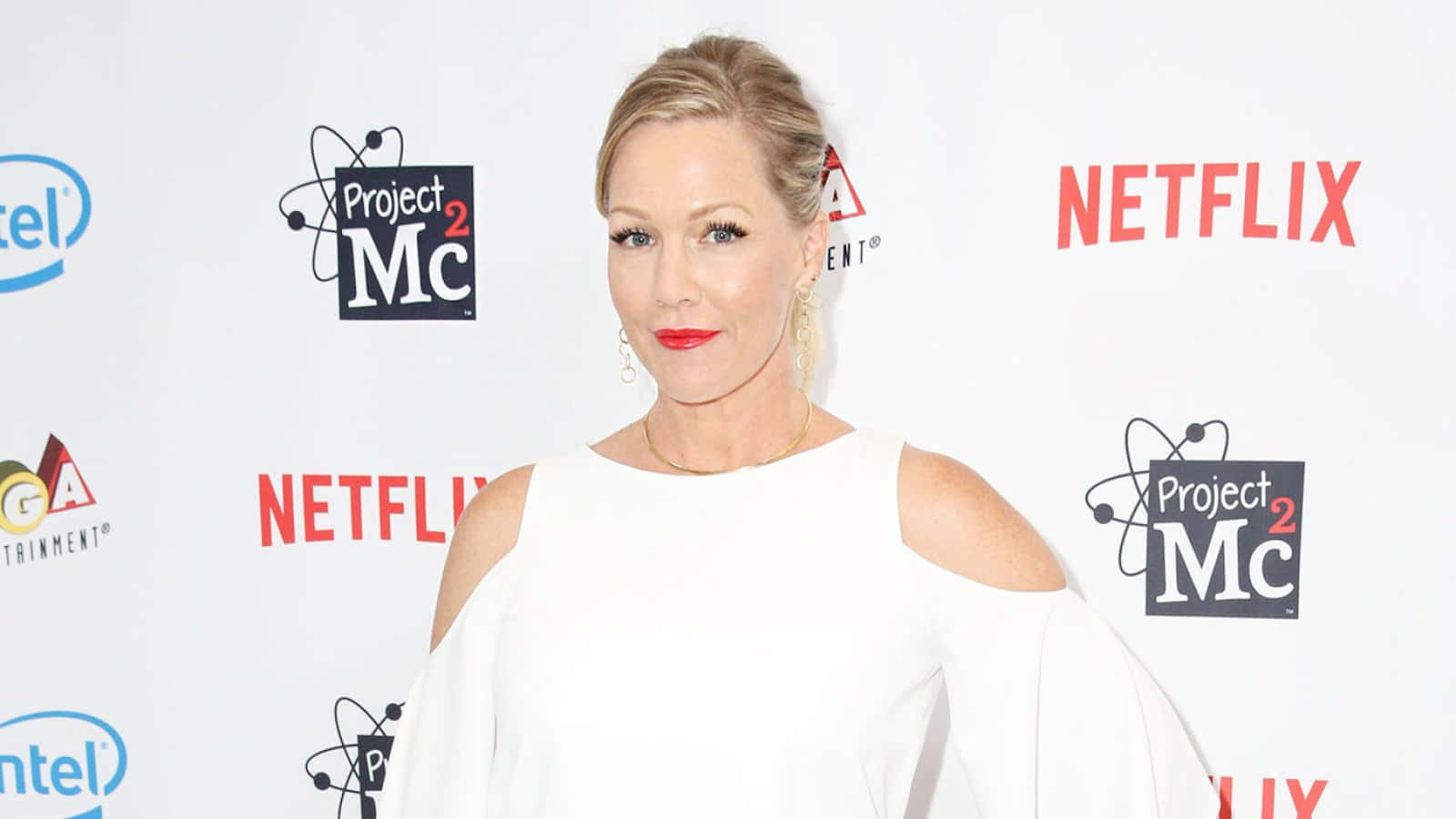 Jennie Garth 桌布 壁紙 — 一位身穿白色露肩連衣裙的女性在紅毯活動中自信地擺姿勢，身後有Netflix和Project Mc2的標誌。