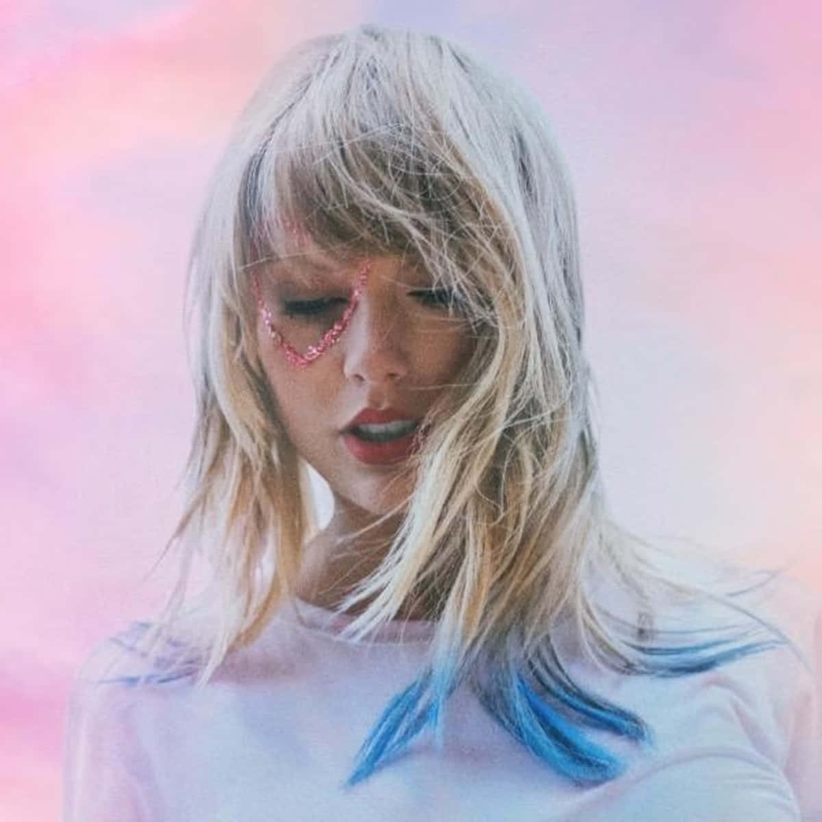 Taylor Swift Lover 桌布 壁紙 — 一位金髮藍色髮尖的女性在柔和的粉紅和紫色天空下低頭凝視。