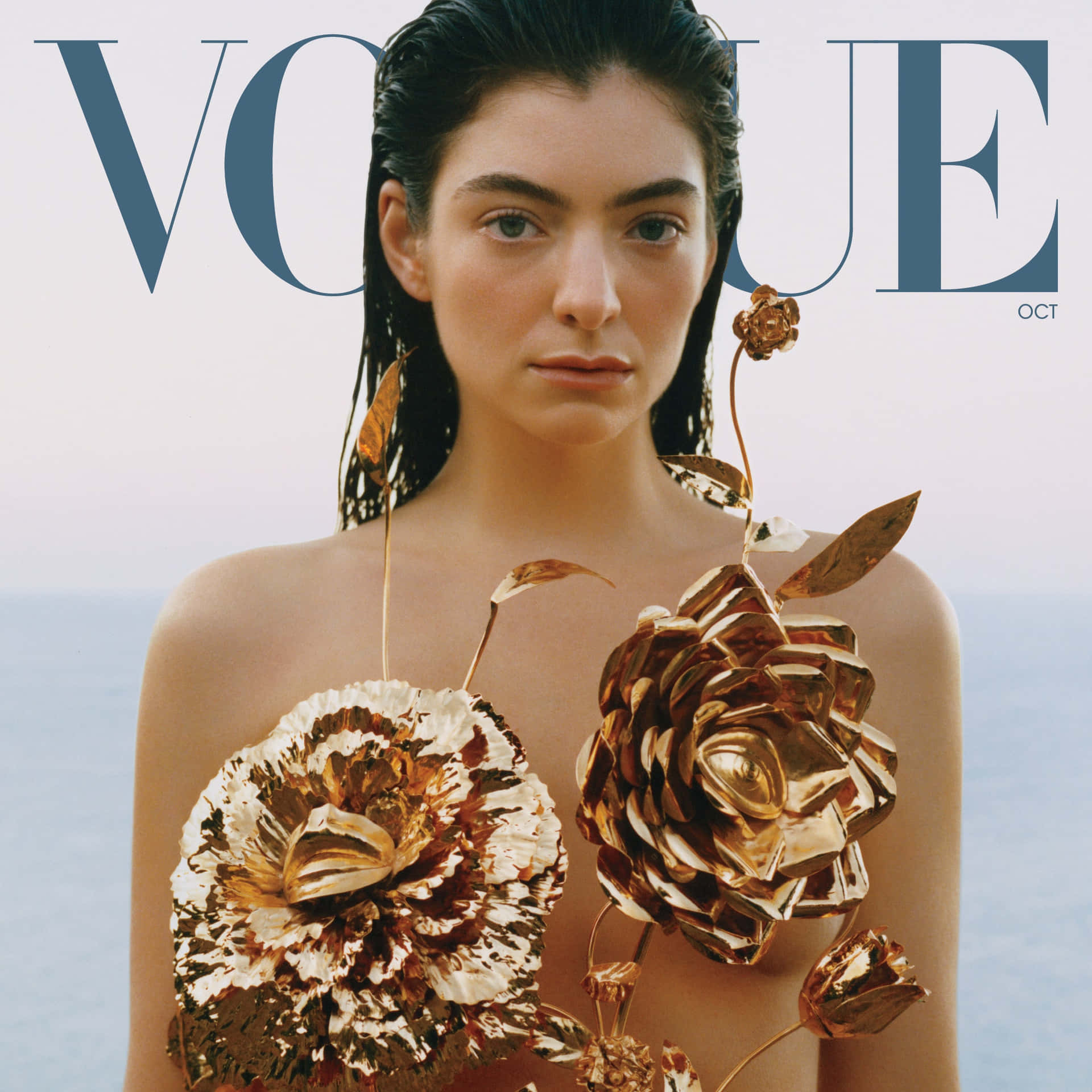  壁紙 — 一名濕髮女性在Vogue雜誌文字下，手持大型金屬金色花朵，背景為淡色海洋。