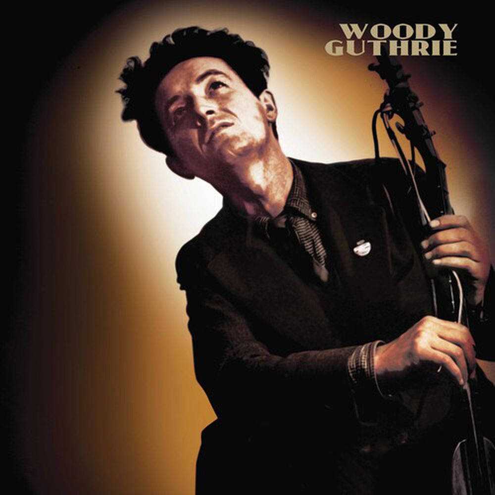 吉他動圖 桌布 壁紙 — Woody Guthrie 向上凝視，手持吉他，在戲劇性的溫暖聚光燈下，背景深色。
