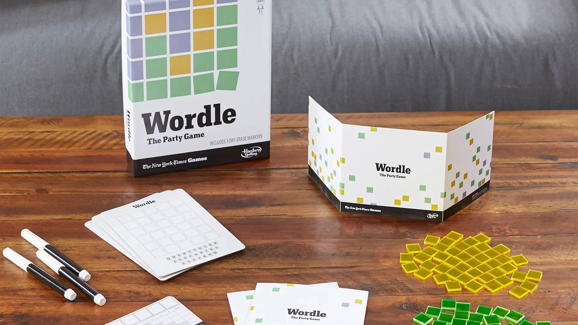 Wordle 桌布 壁紙 — Wordle 派對遊戲盒及組件排列在木桌上，背景有灰色沙發。