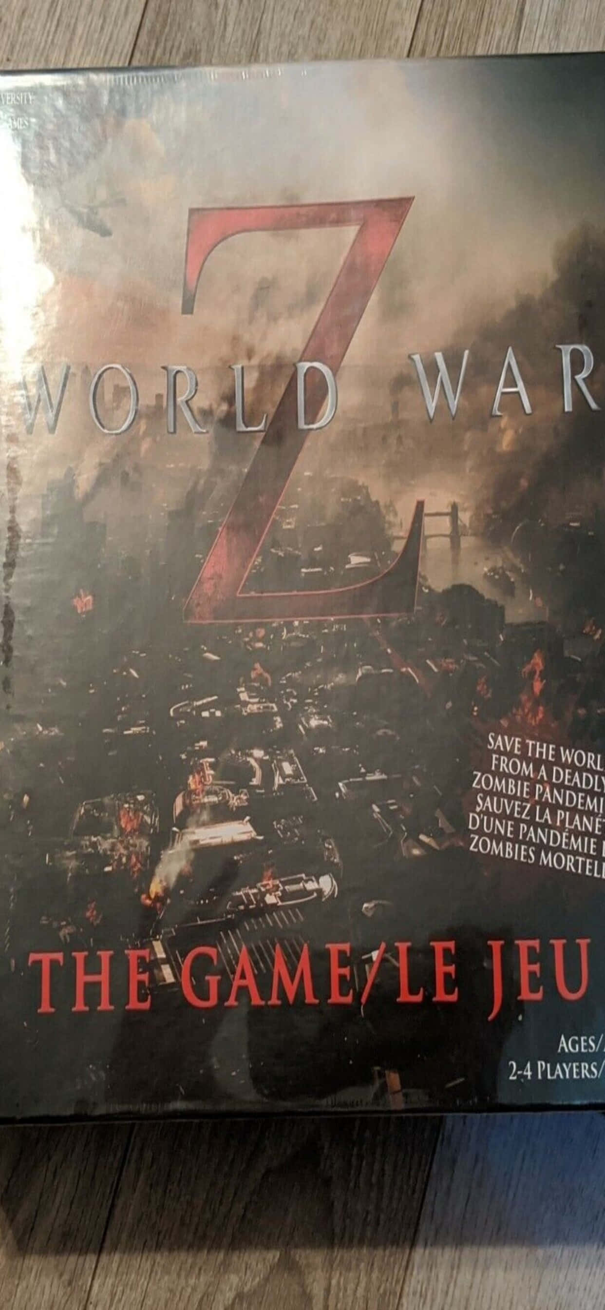 遊戲 桌布 壁紙 — 《World War Z》的遊戲盒展示了一個混亂的殭屍末日場景，有燃燒的汽車和一個巨大的紅色Z標誌，背景是煙霧瀰漫的天空。