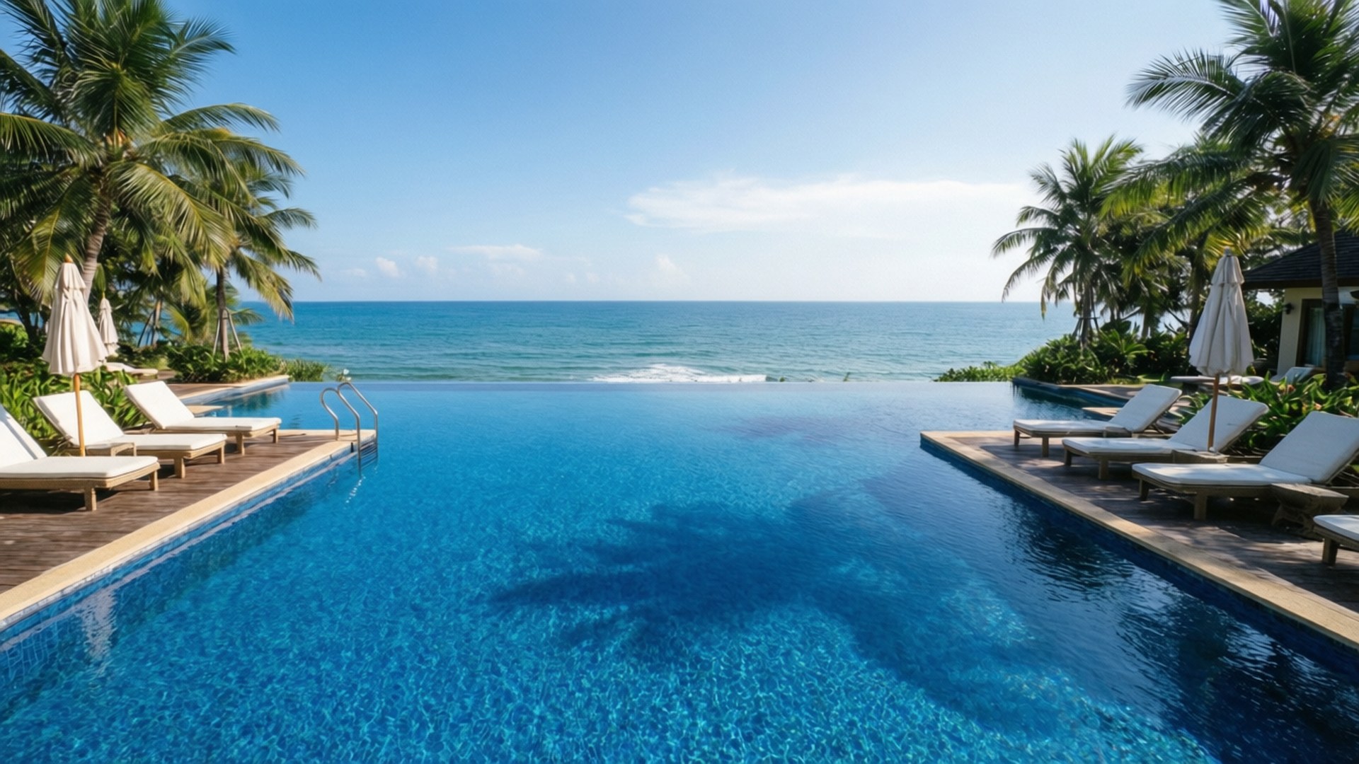 Infinity Pool Luxury 壁紙 — 無邊際泳池與碧綠海洋完美融合，在藍天白雲和搖曳棕櫚樹的襯托下。
