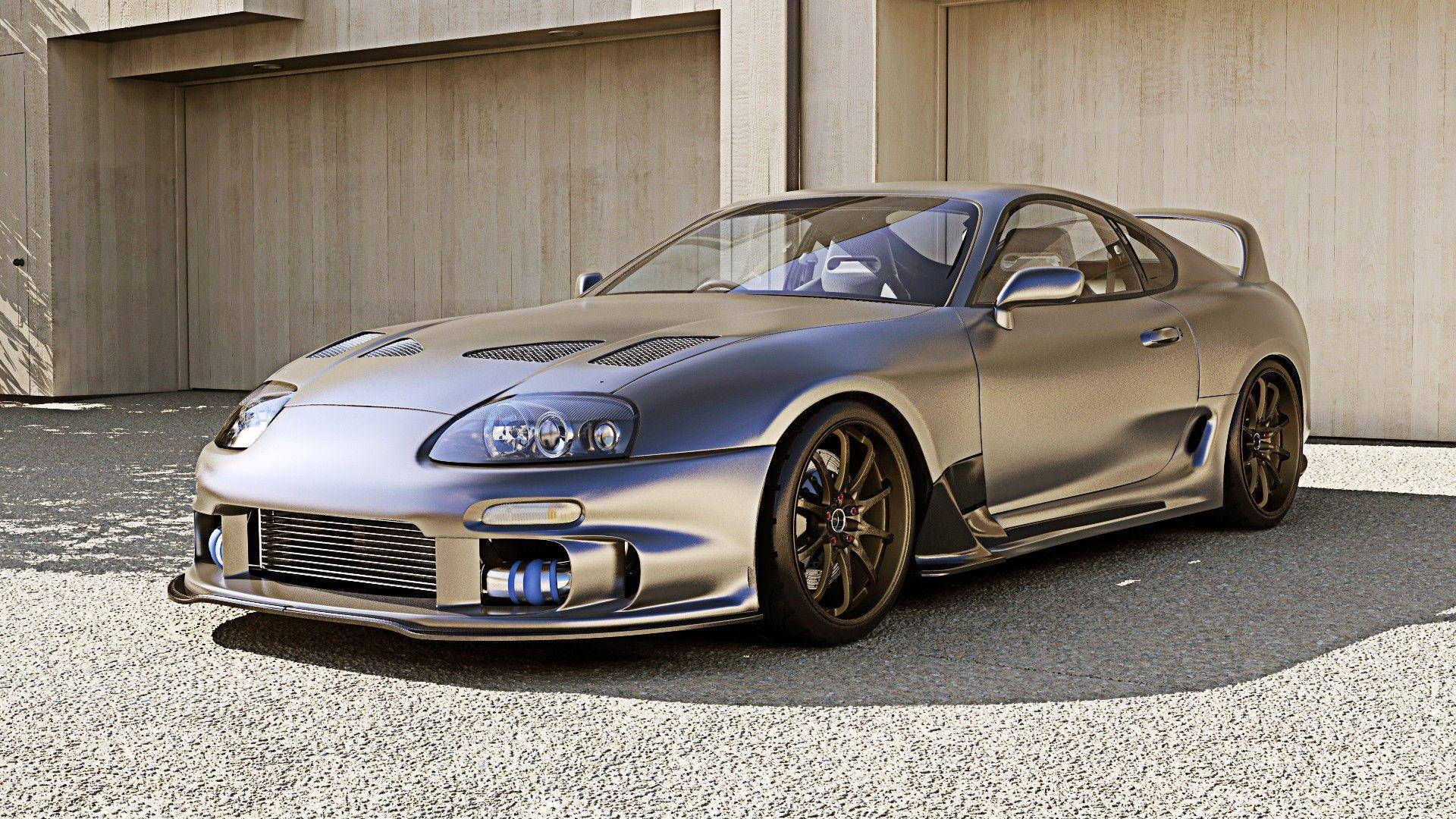 霧面銀色豐田Supra跑車停在混凝土車庫附近的碎石地上。 — Toyota Supra 壁紙