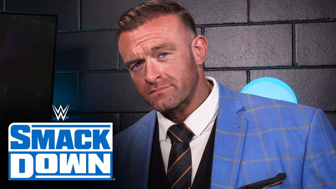  壁紙 — WWE摔角手Finn Balor身穿藍色格紋西裝，在深色磚牆前擺出得意表情，背景有SmackDown標誌。