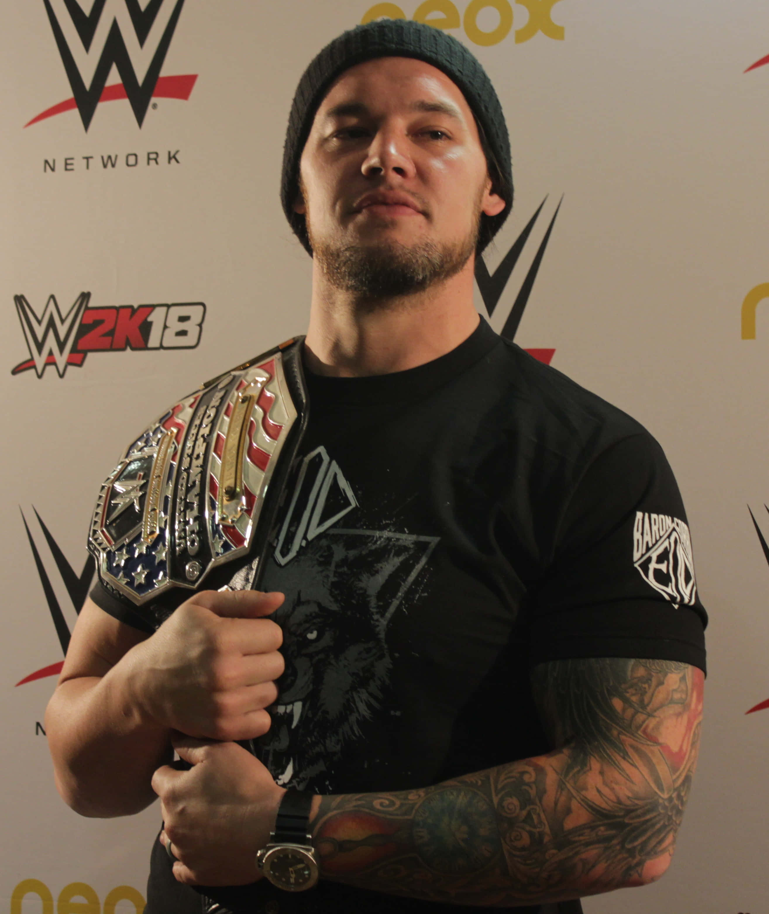 WWE 桌布 壁紙 — WWE 摔角手紋身手臂在品牌背景的新聞發布會上手持冠軍腰帶。
