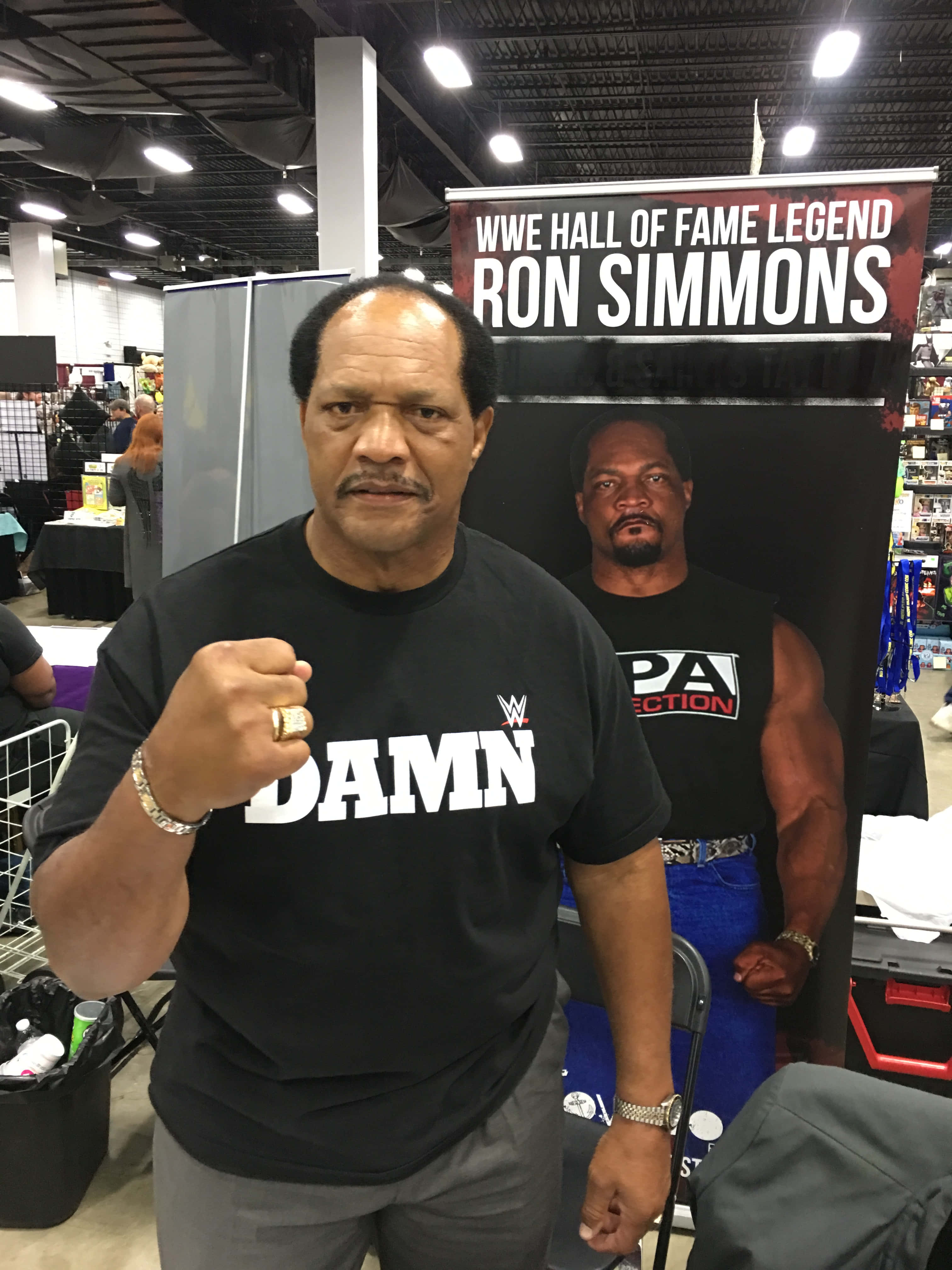 摔角 桌布 壁紙 — WWE名人堂成員Ron Simmons自信地穿著黑色'DAMN'T恤，在一個有宣傳背景的會議上擺姿勢。
