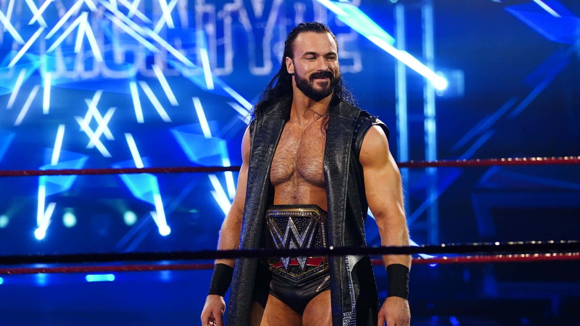 WWE 桌布 壁紙 — WWE摔角手Seth Rollins自信地站在擂台上，在明亮的藍色舞台燈光下佩戴著他的冠軍腰帶。