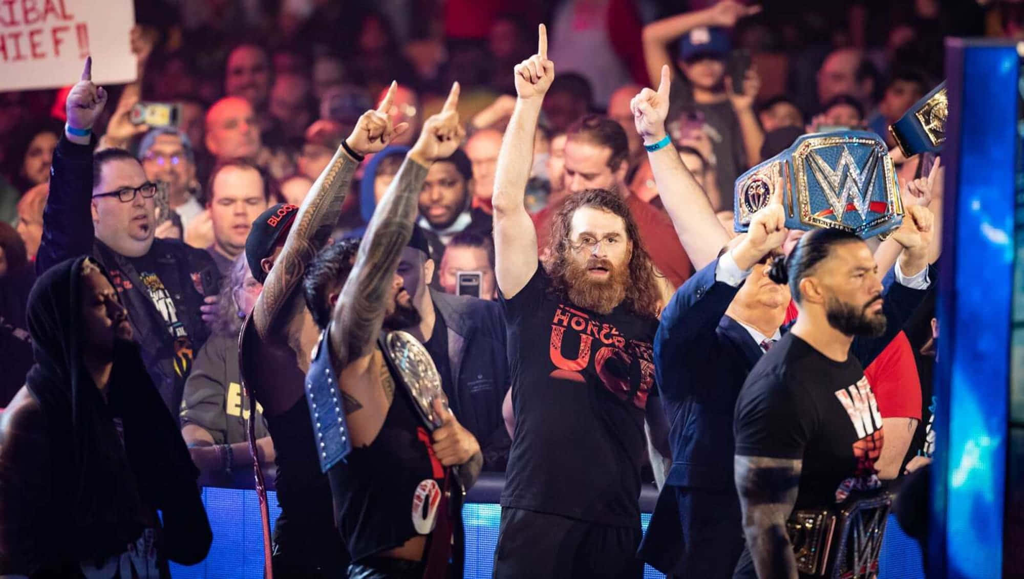sami zayn 桌布 壁紙 — WWE摔角手在興奮的人群面前高舉冠軍腰帶慶祝勝利。