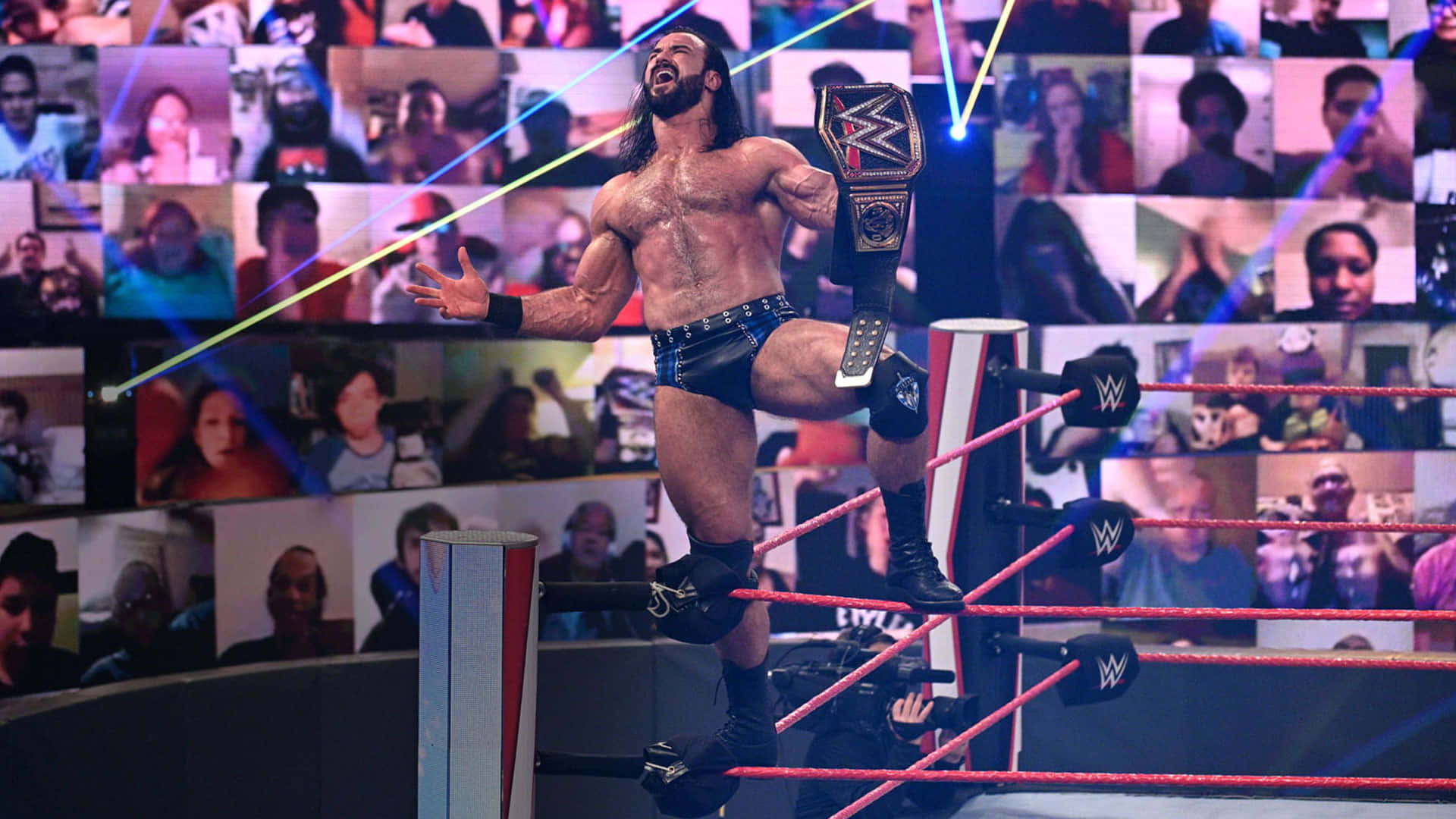 WWE 桌布 壁紙 — WWE摔角手留長髮、腰間冠軍腰帶，在粉絲視頻螢幕背景下，勝利地站在擂台繩索上。