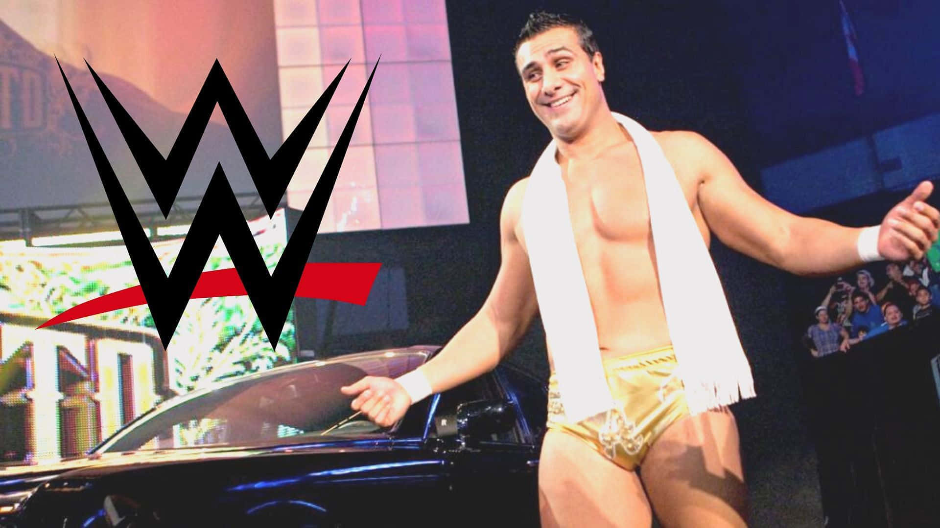 WWE 桌布 壁紙 — WWE摔角手自信微笑，身穿金色短褲，白色毛巾披在肩上，旁邊有一輛黑色汽車。