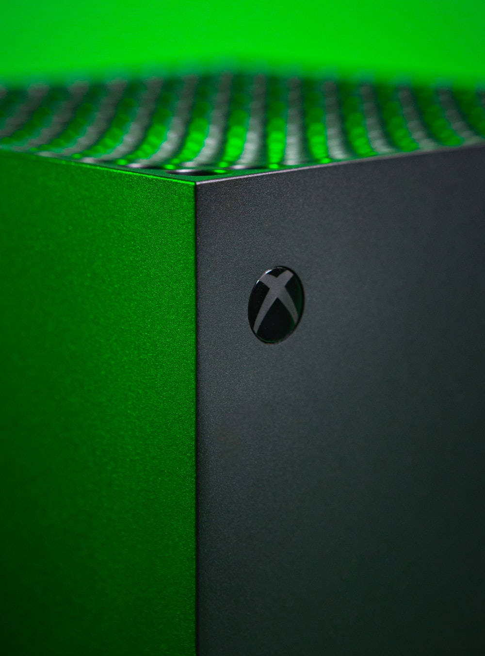 X 桌布 壁紙 — Xbox 主機特寫，帶有充滿活力的綠色發光通風口和霧面黑色外殼。