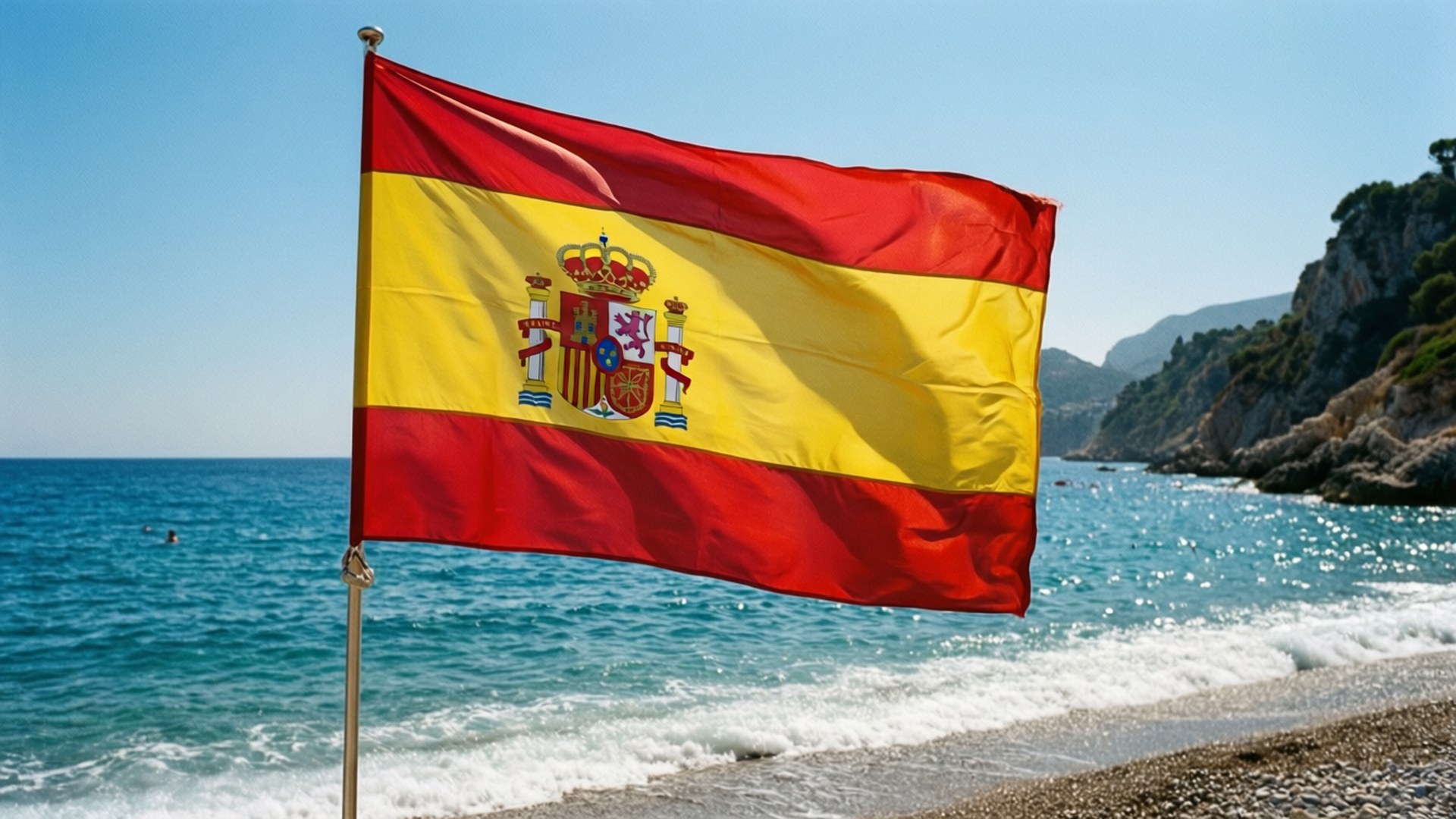 Spanish Flag Beach 壁紙 — 西班牙國旗在陽光明媚的海灘上自豪地飄揚，背景是碧綠的海洋和岩石峭壁。