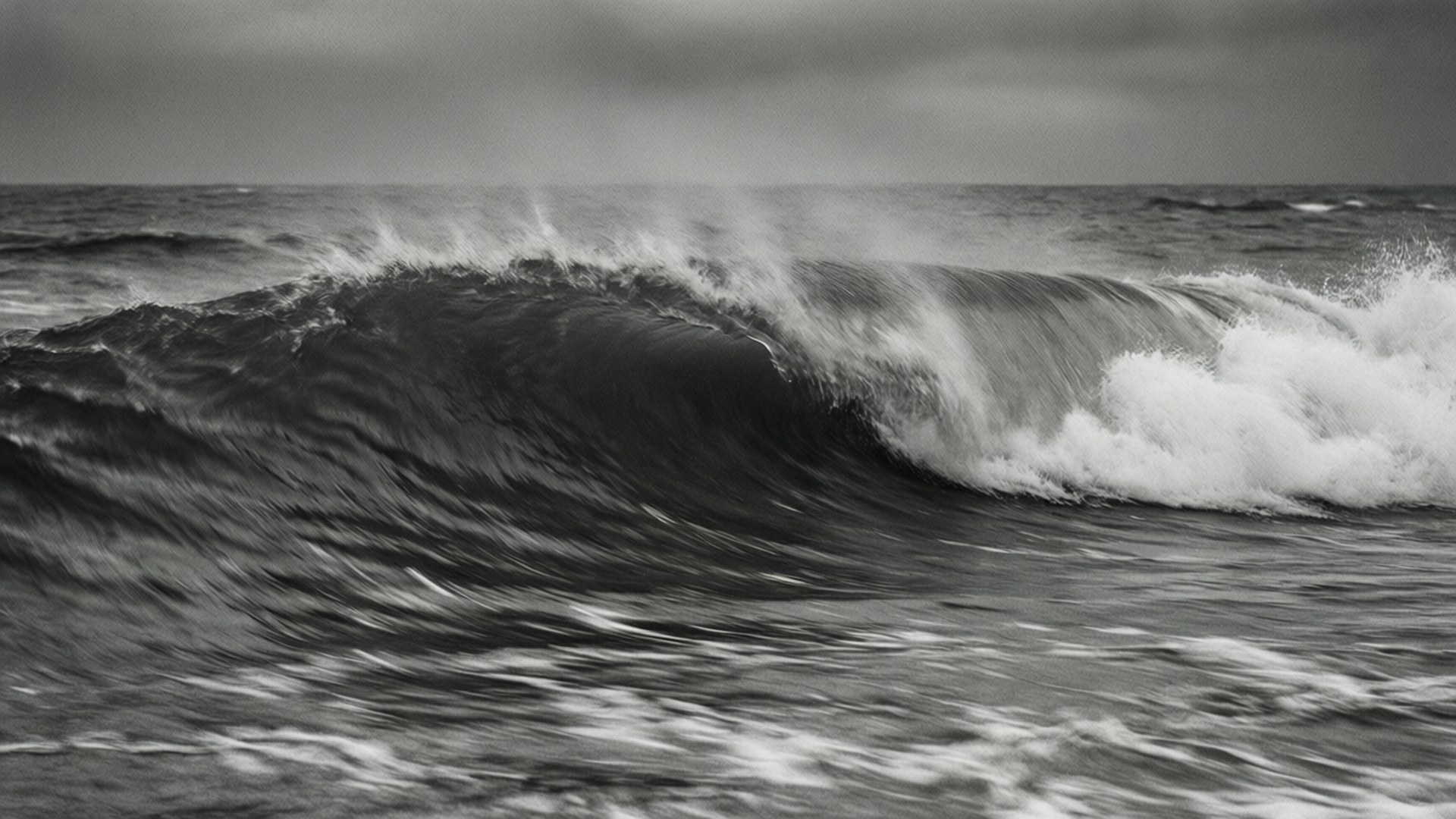 Gray Ocean Waves 壁紙 — 戲劇性的單色波浪捲起並破碎，帶有泡沫般的白色飛沫，映襯著暴風雨般的灰色天空。