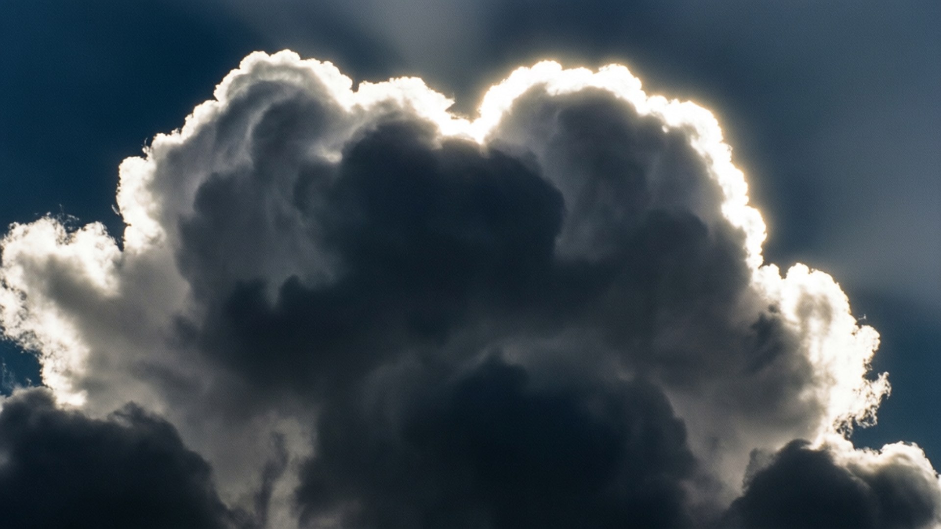 Silver Lining 壁紙 — 戲劇性的積雲從背後被陽光照射，在深藍色的天空中投射出銳利的白色邊緣。