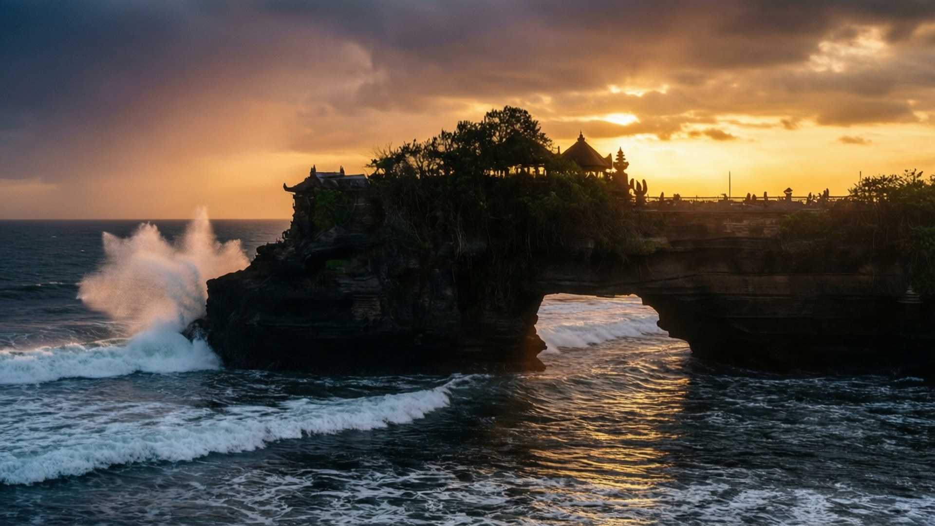 Tanah Lot Temple Sunset 壁紙 — 夕陽將大海和岩石島上的寺廟沐浴在金色光芒中，海浪拍打其底部。