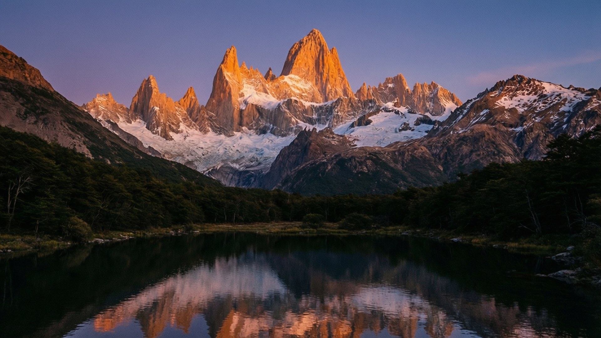 Argentina 壁紙 — 夕陽將鋸齒狀的雪峰沐浴在金色光芒中，完美地倒映在黑暗森林環繞的平靜湖面上。
