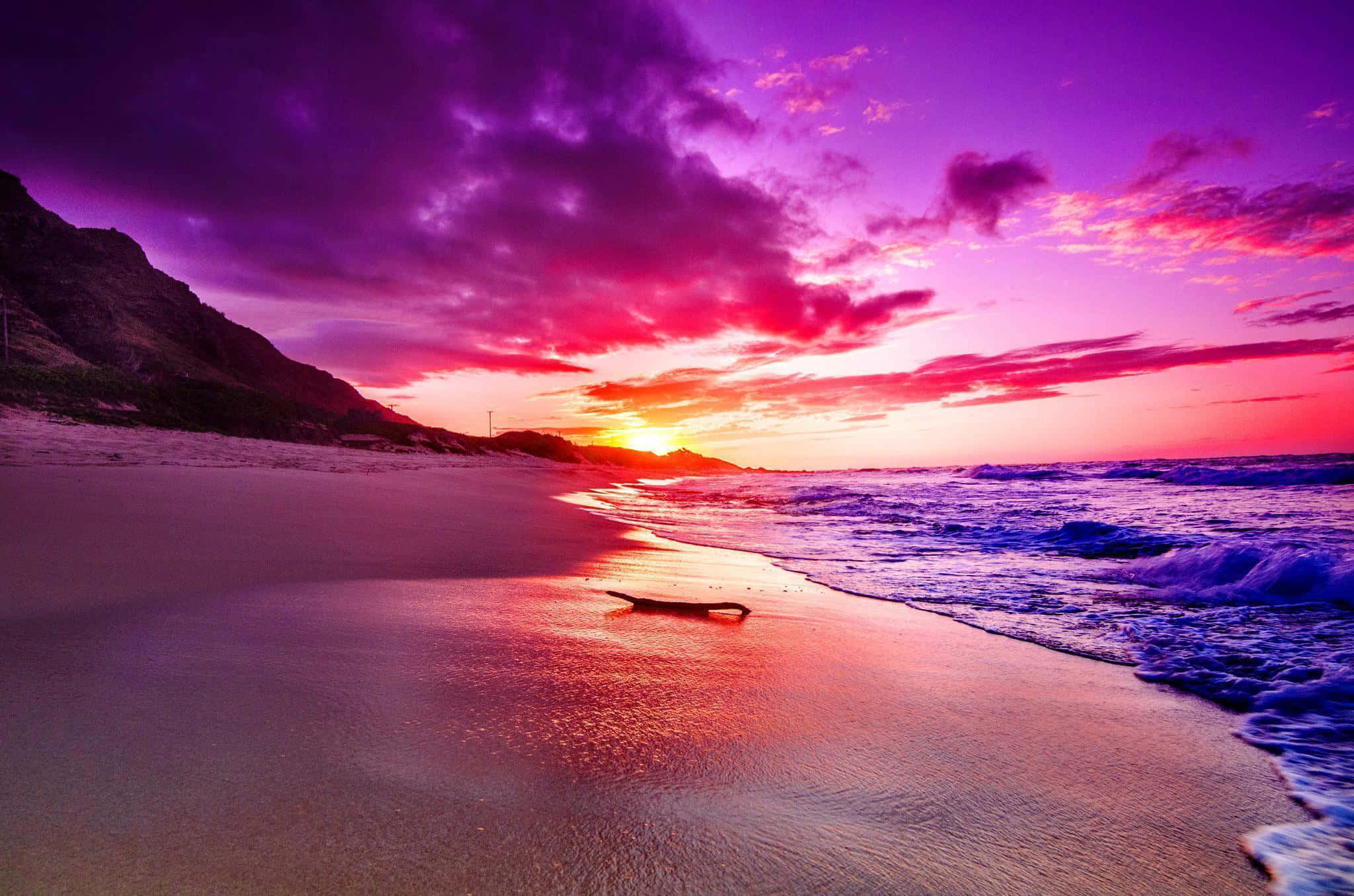 Colorful Sunset 桌布 壁紙 — 夕陽將沙灘染成洋紅色和深紅色，海浪在戲劇性的紫色天空下拍打著海岸。