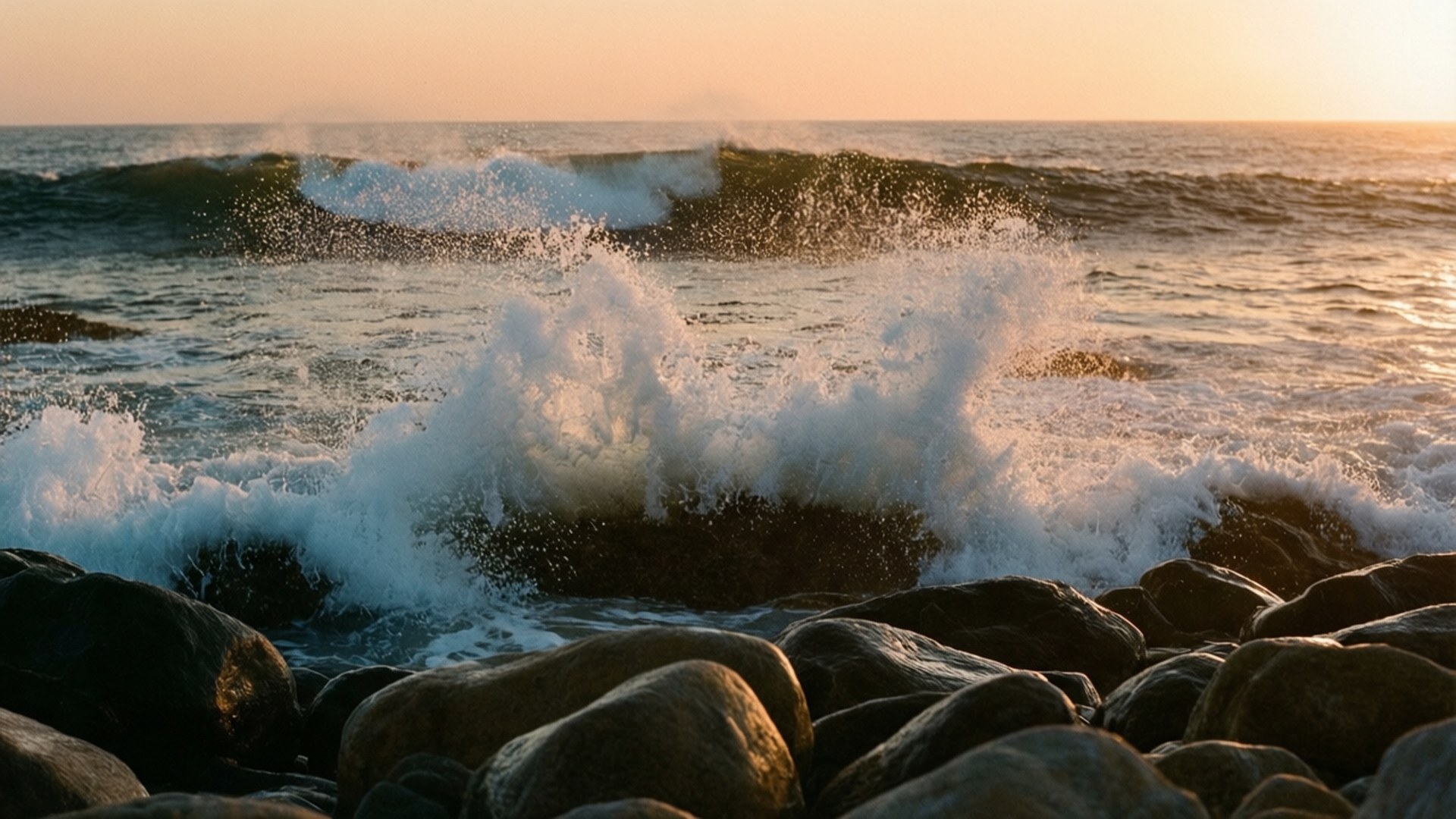 Shore Sunset Waves 壁紙 — 夕陽下，海浪拍打黑色岩石，激起白色水花，在金色光線中飛濺。