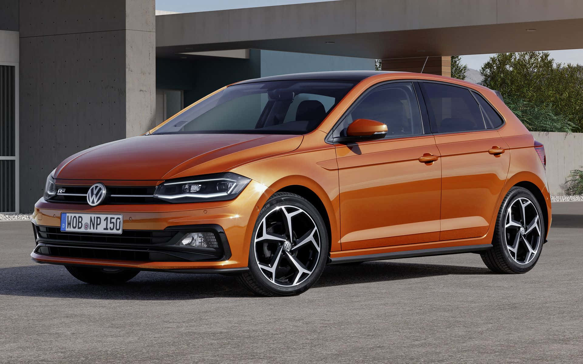 Volkswagen Polo 桌布 壁紙 — 一輛鮮橙色的福斯Polo掀背車，配備時尚黑色合金輪圈，停放在現代混凝土結構下。