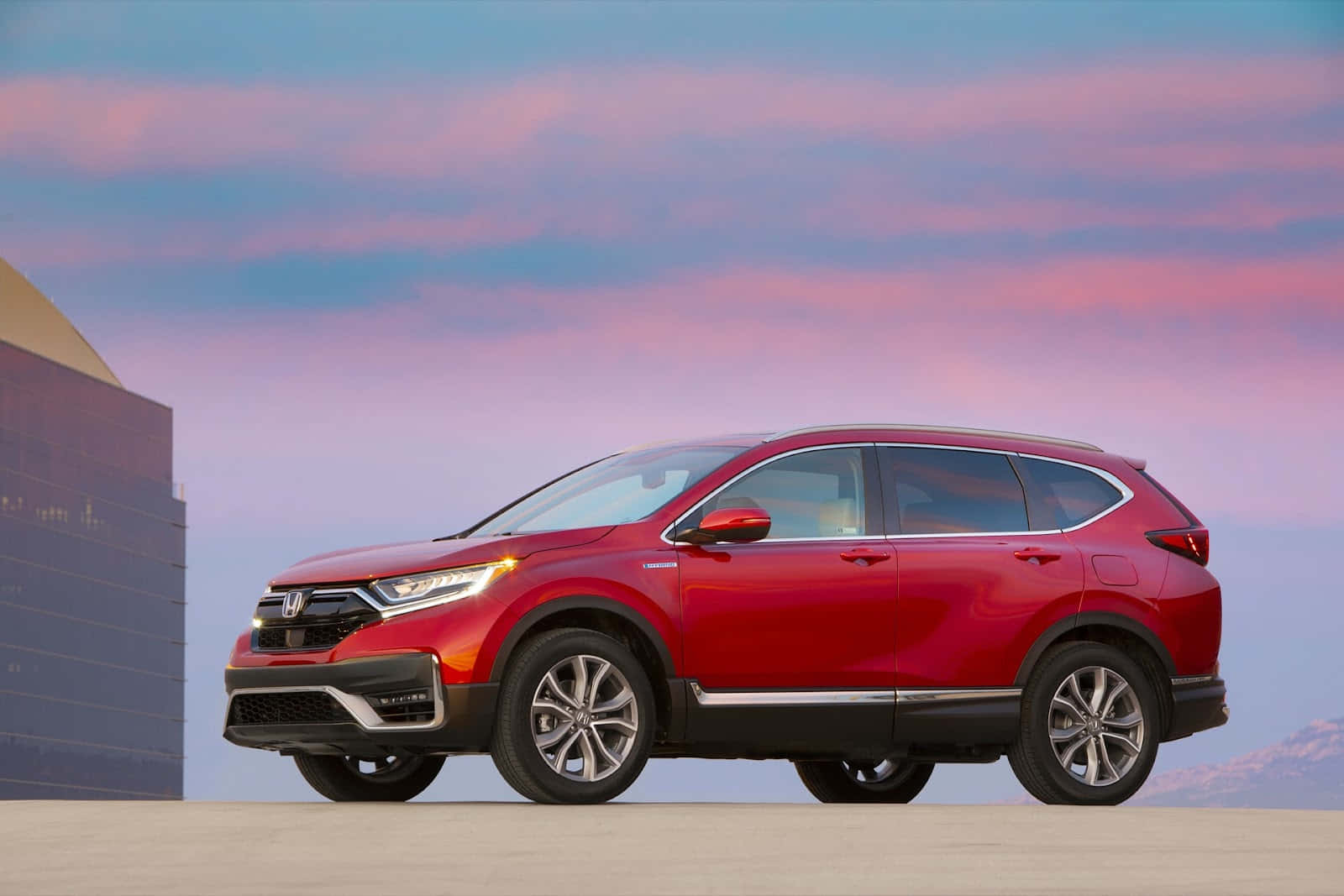 Honda Cr-v 桌布 壁紙 — 一輛鮮紅色的本田CR-V SUV停放在混凝土表面上，背景是粉彩粉紅和藍色的暮色天空，以及現代建築。