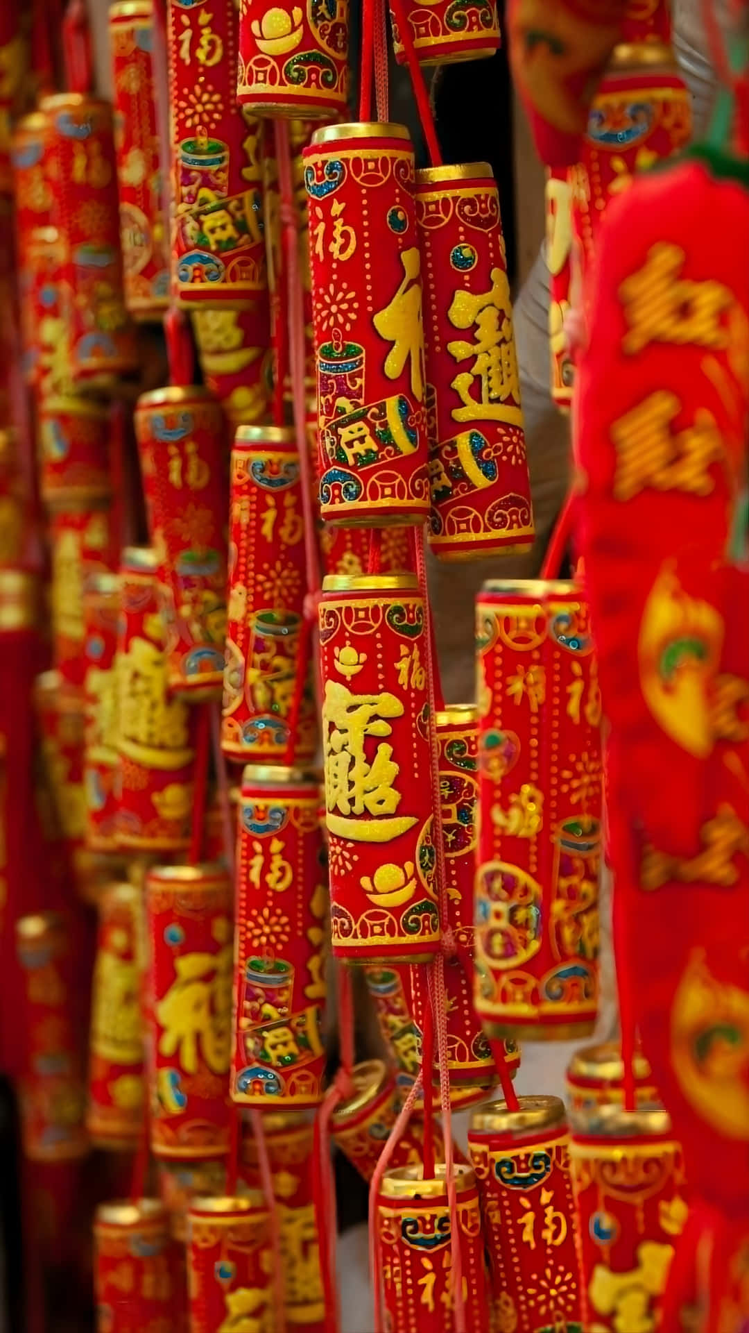  壁紙 — 鮮紅色的圓柱形燈籠，飾有金色中文字和節日圖案，密集地懸掛在喜慶的展示中。