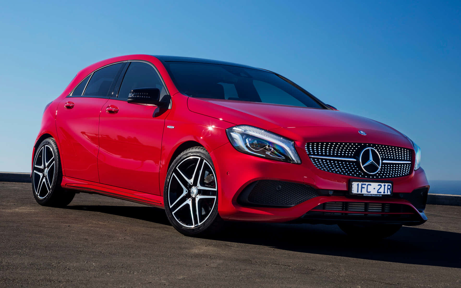 Mercedes Benz A-class 桌布 壁紙 — 一輛鮮紅色的梅賽德斯-奔馳A級跑車在晴朗的藍天下閃耀著明亮的陽光。