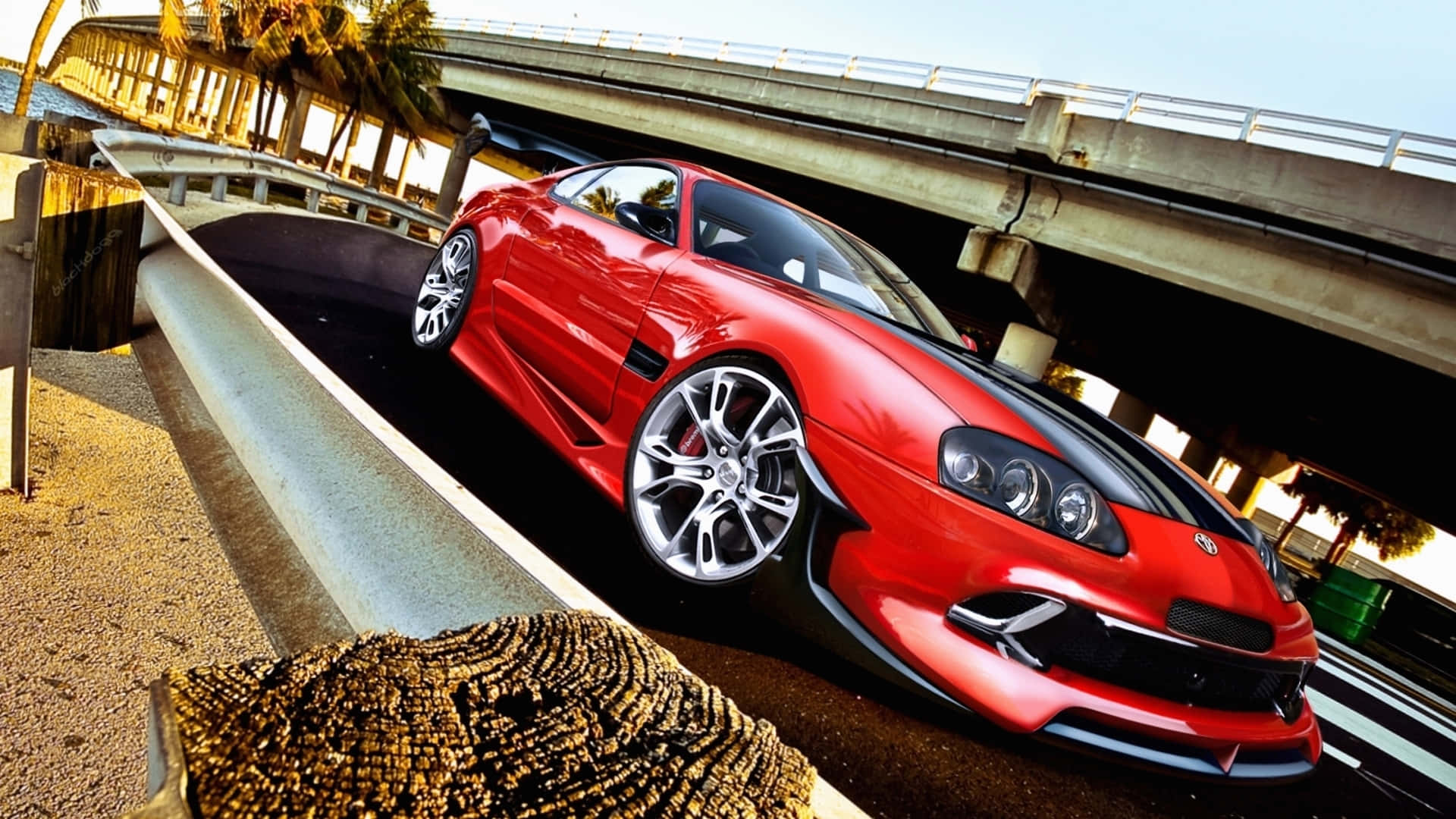紅色跑車在天橋下疾馳，背景有棕櫚樹。 — Toyota Supra 壁紙