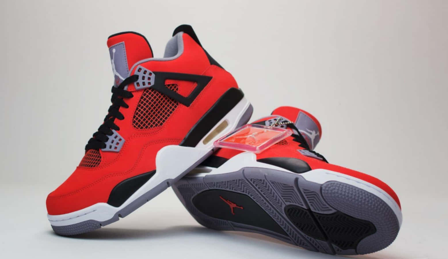 紅色和黑色的Jordan 4運動鞋，白色鞋底和可見的Air緩衝。 — Air Jordan 壁紙