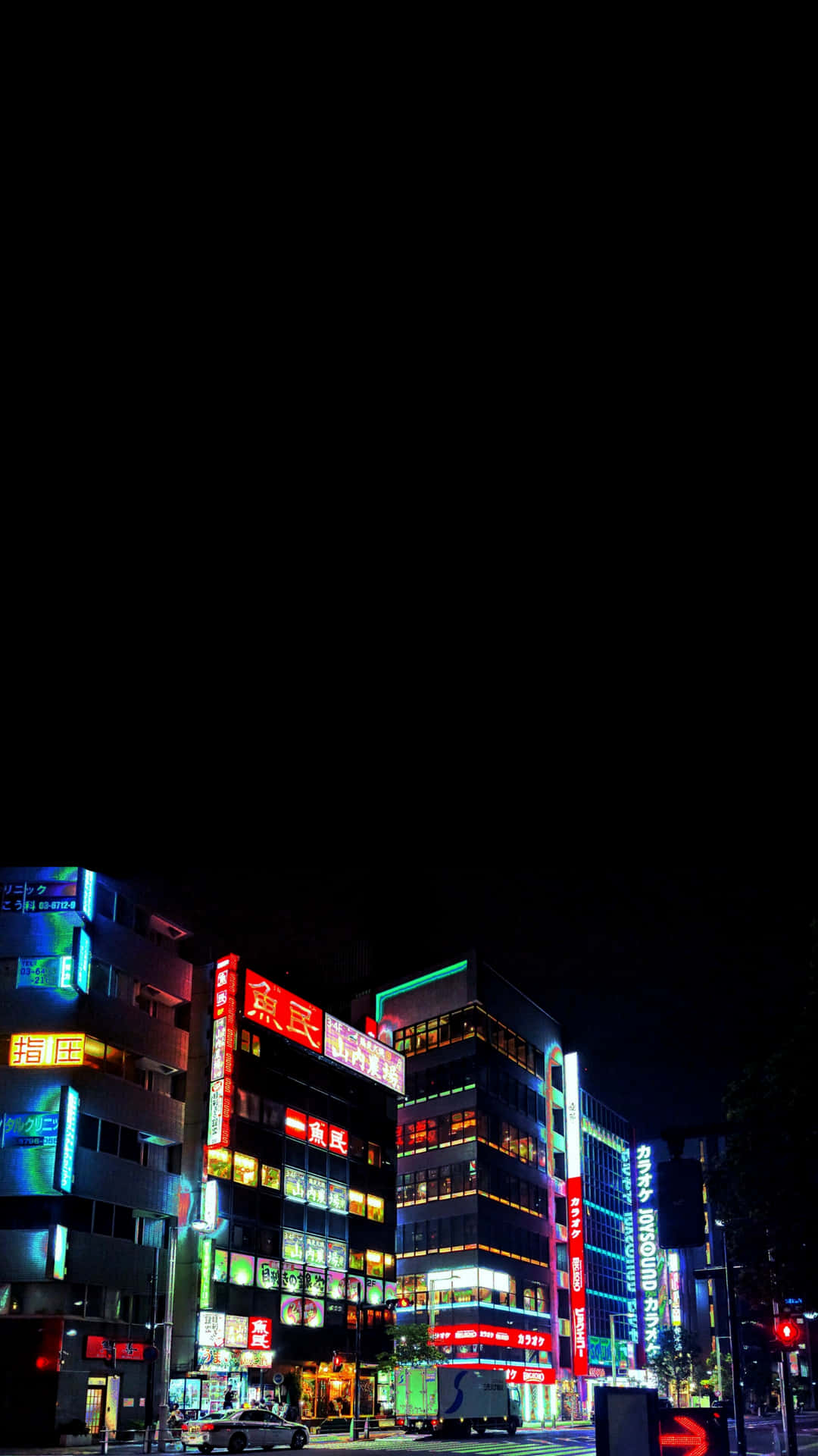日本夜晚霓虹燈照亮的城市街道，帶有發光的招牌和黑暗的天空。 — Oled 壁紙