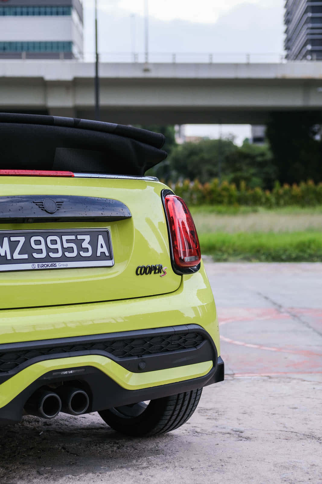 Mini Cooper S 桌布 壁紙 — 鮮豔的青檸綠色MINI Cooper S敞篷車停放在城市高架橋下，背景有模糊的城市建築。