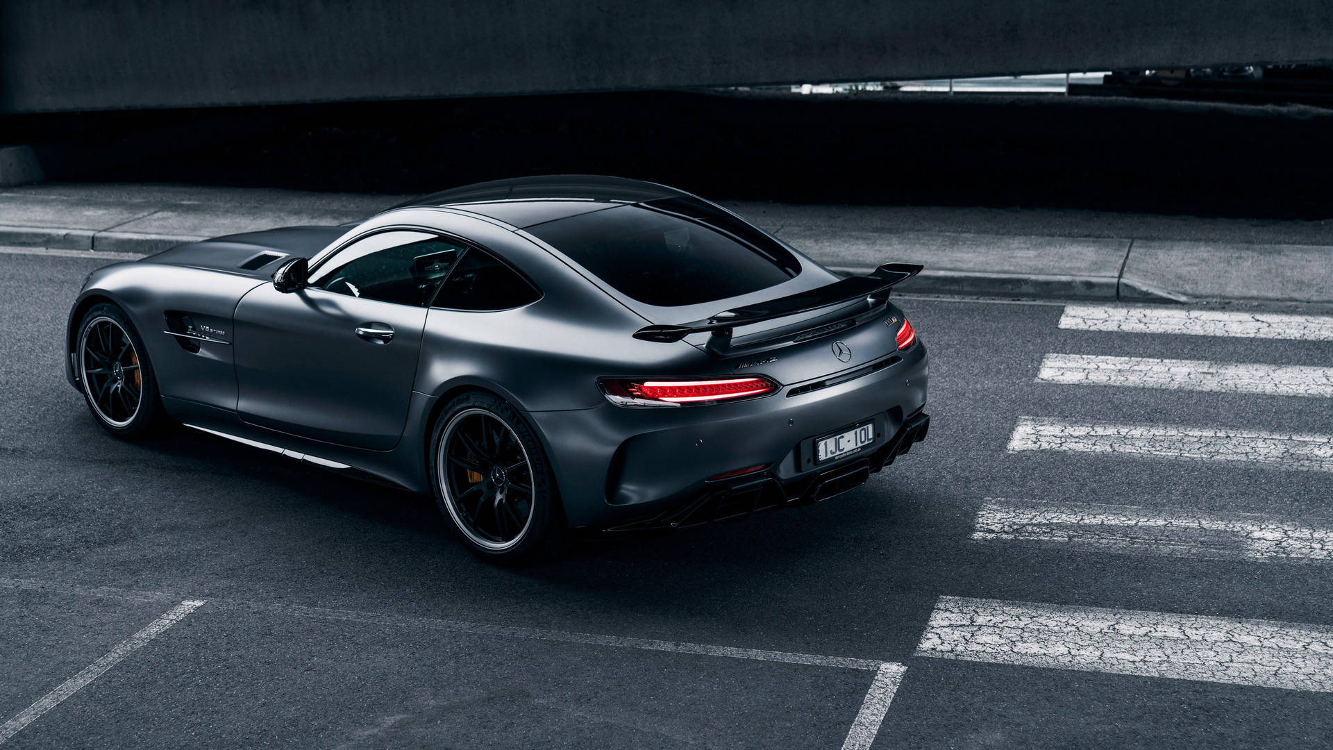 消光黑色跑車帶紅色尾燈停放在天橋下的城市街道上。 — Amg Gt R 壁紙