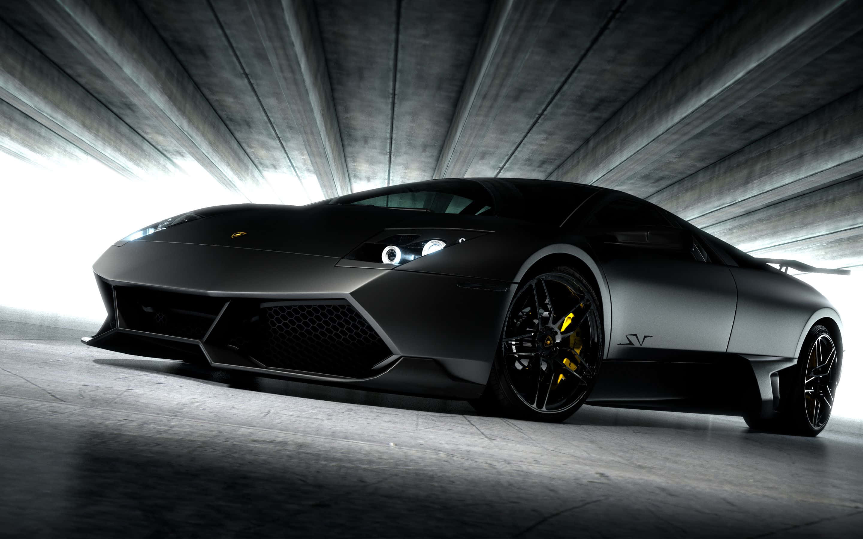 Lamborghini Murciélago 桌布 壁紙 — 一輛光滑的消光黑色藍寶堅尼Reventon跑車，配備黃色制動卡鉗，在混凝土隧道中被戲劇性地照亮。