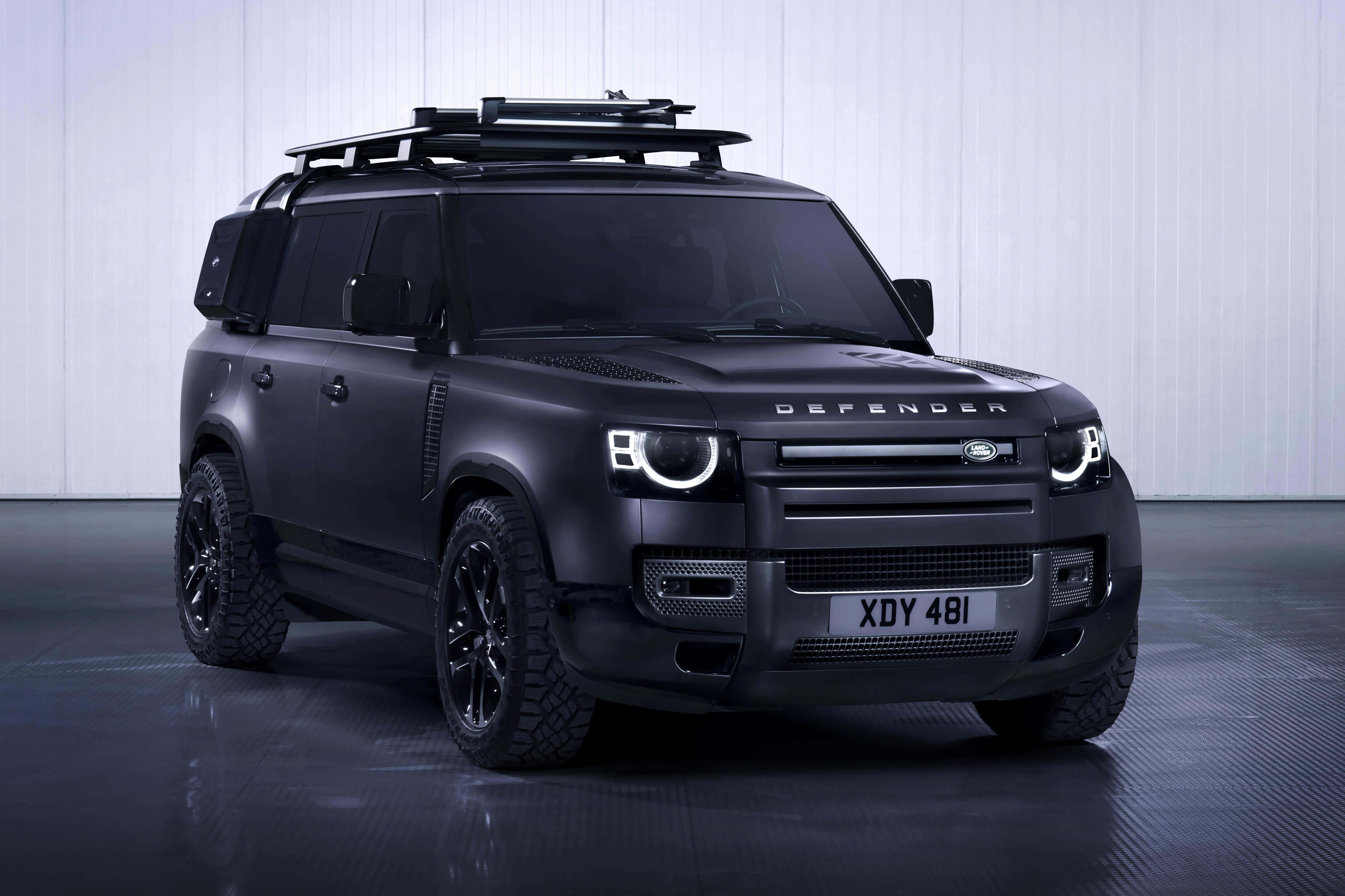 Land Rover Defender 桌布 壁紙 — 一輛消光黑色的Land Rover Defender配備車頂架，位於極簡風格的工作室中，地板具有反射效果，牆面為垂直鑲板。