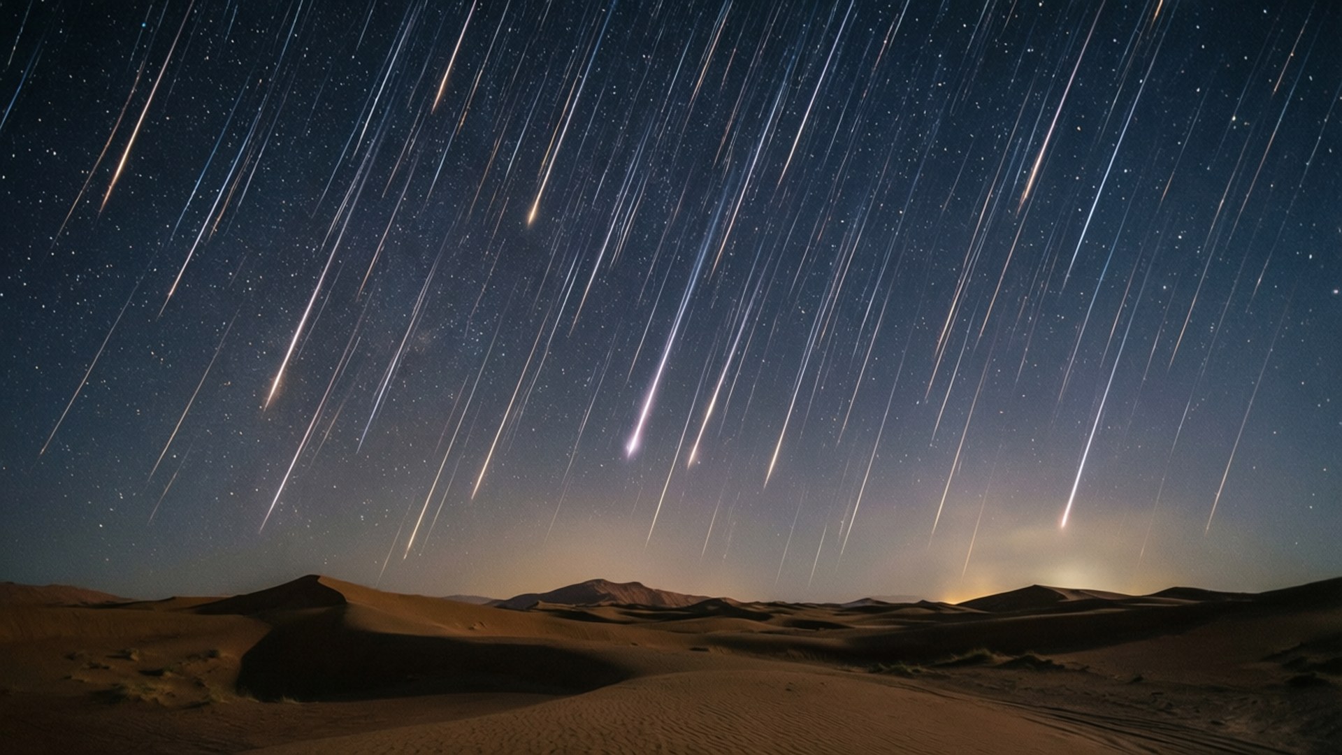Desert Meteor Shower 壁紙 — 星軌劃過深藍色的夜空，下方是廣闊的沙漠景觀和起伏的沙丘。