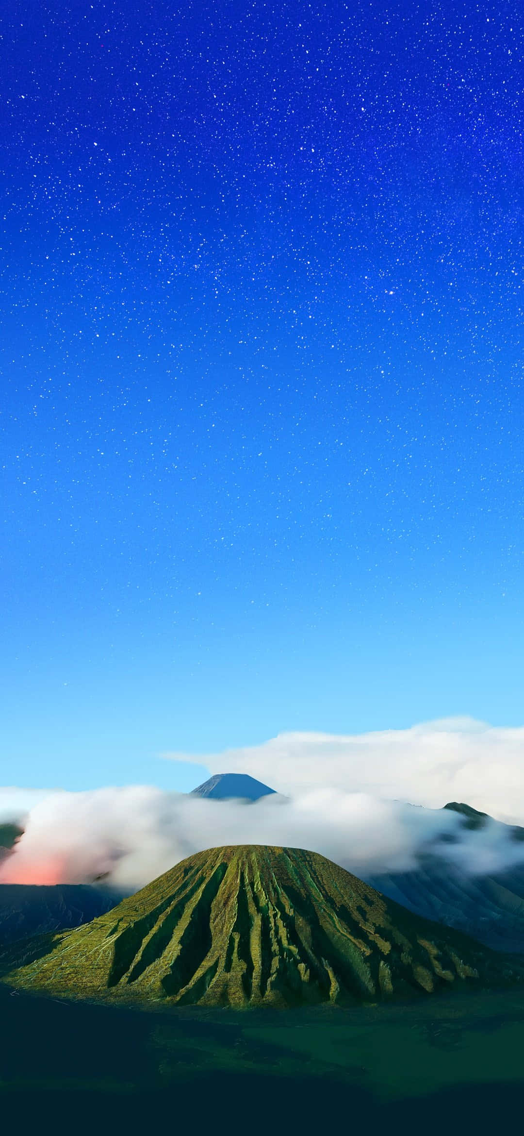 日出時，在繁星點點的藍天下，綠色山峰從雲層中浮現。 — iPhone 13 Pro 壁紙