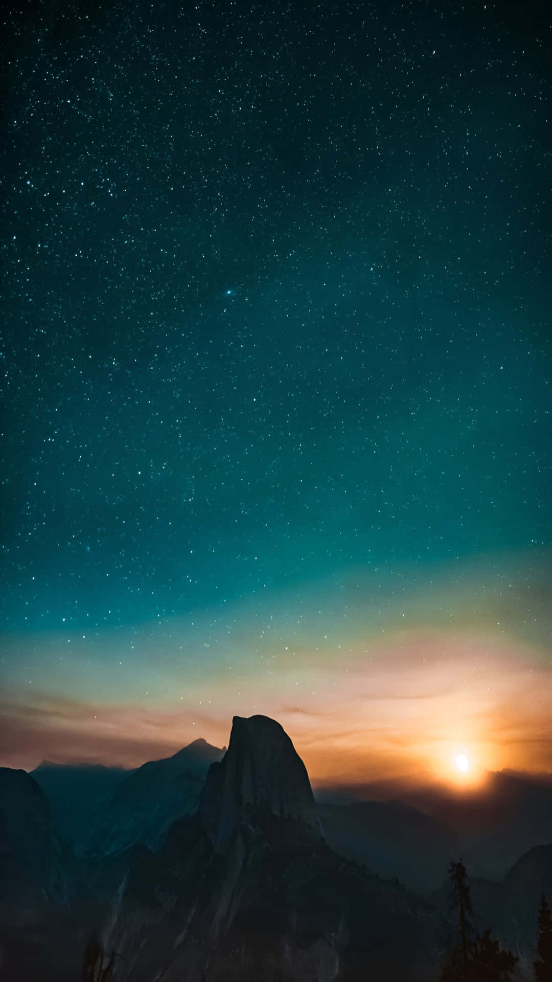  壁紙 — 雄偉的山峰在繁星點點的暮色天空中形成剪影，地平線上有發光的太陽。