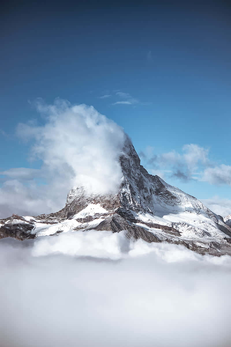  壁紙 — 雄偉的雪山峰頂在清澈的藍天下穿過蓬鬆的白雲。