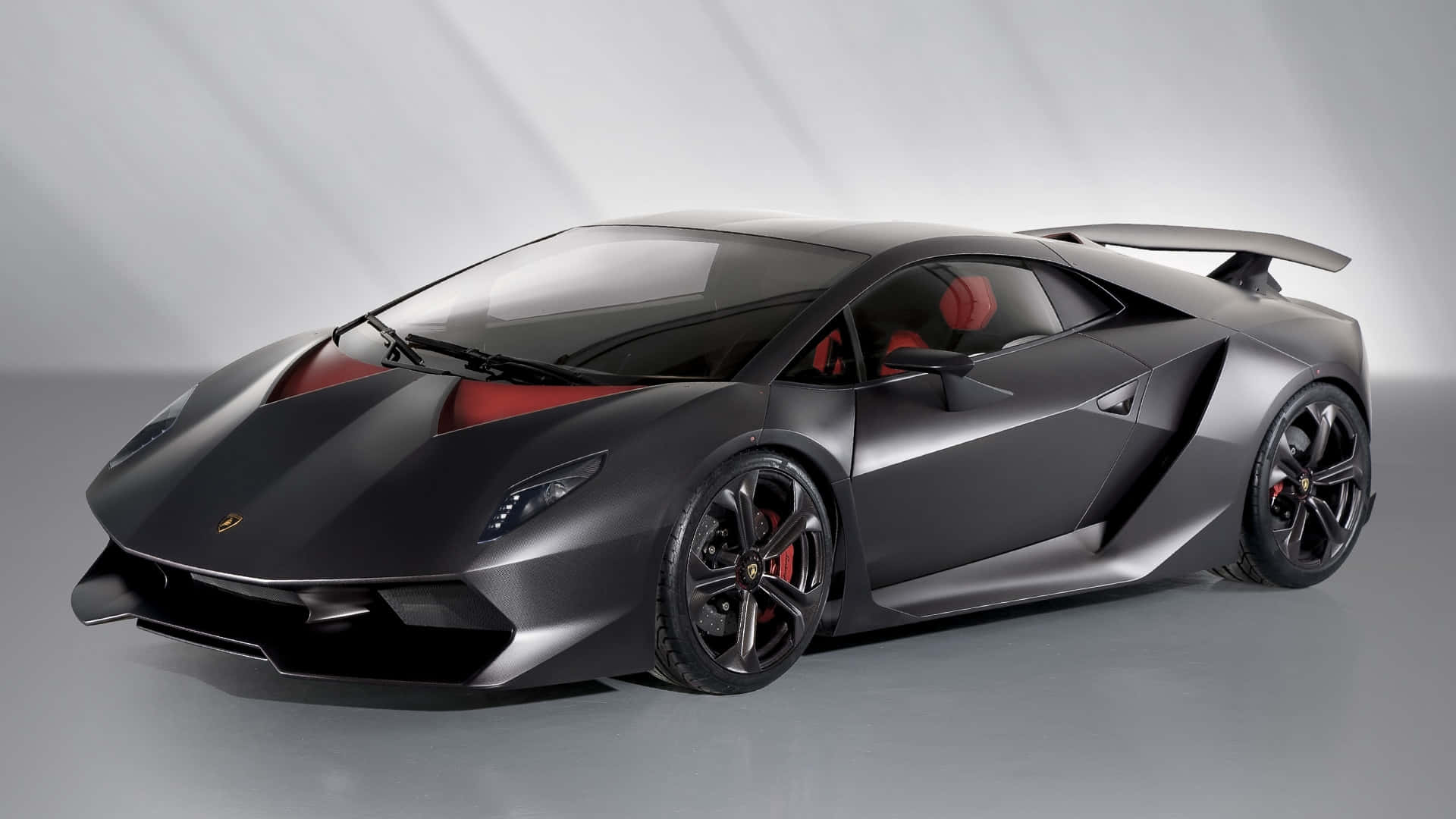 Lamborghini Sesto Elemento 桌布 壁紙 — 一輛時尚的啞光黑色藍寶堅尼跑車，帶有紅色點綴和黑色輪圈，擺放在簡約的攝影棚環境中。